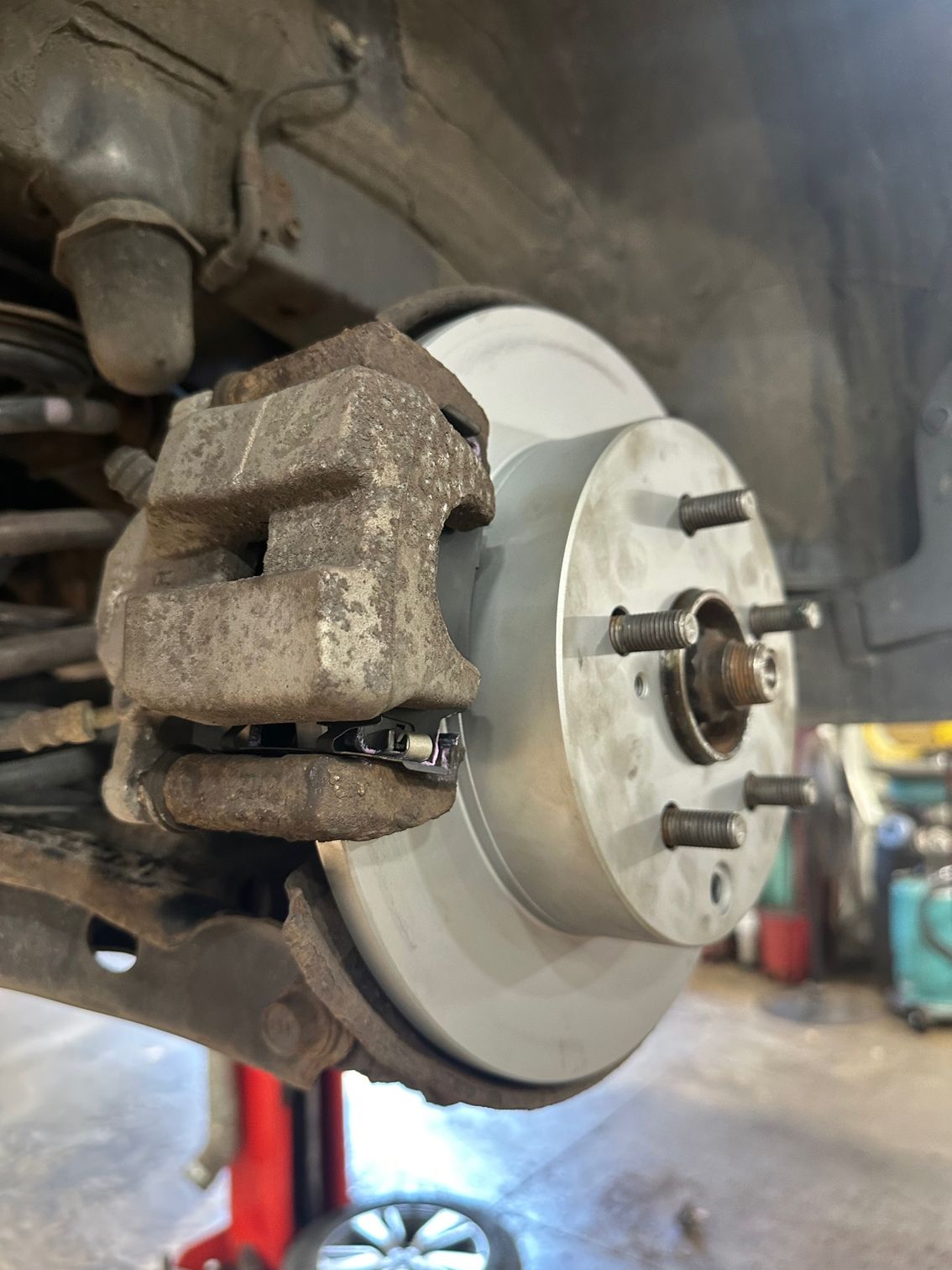 Disc brake and caliper on vehicle in shop | Lou's Car Care Center, Inc.