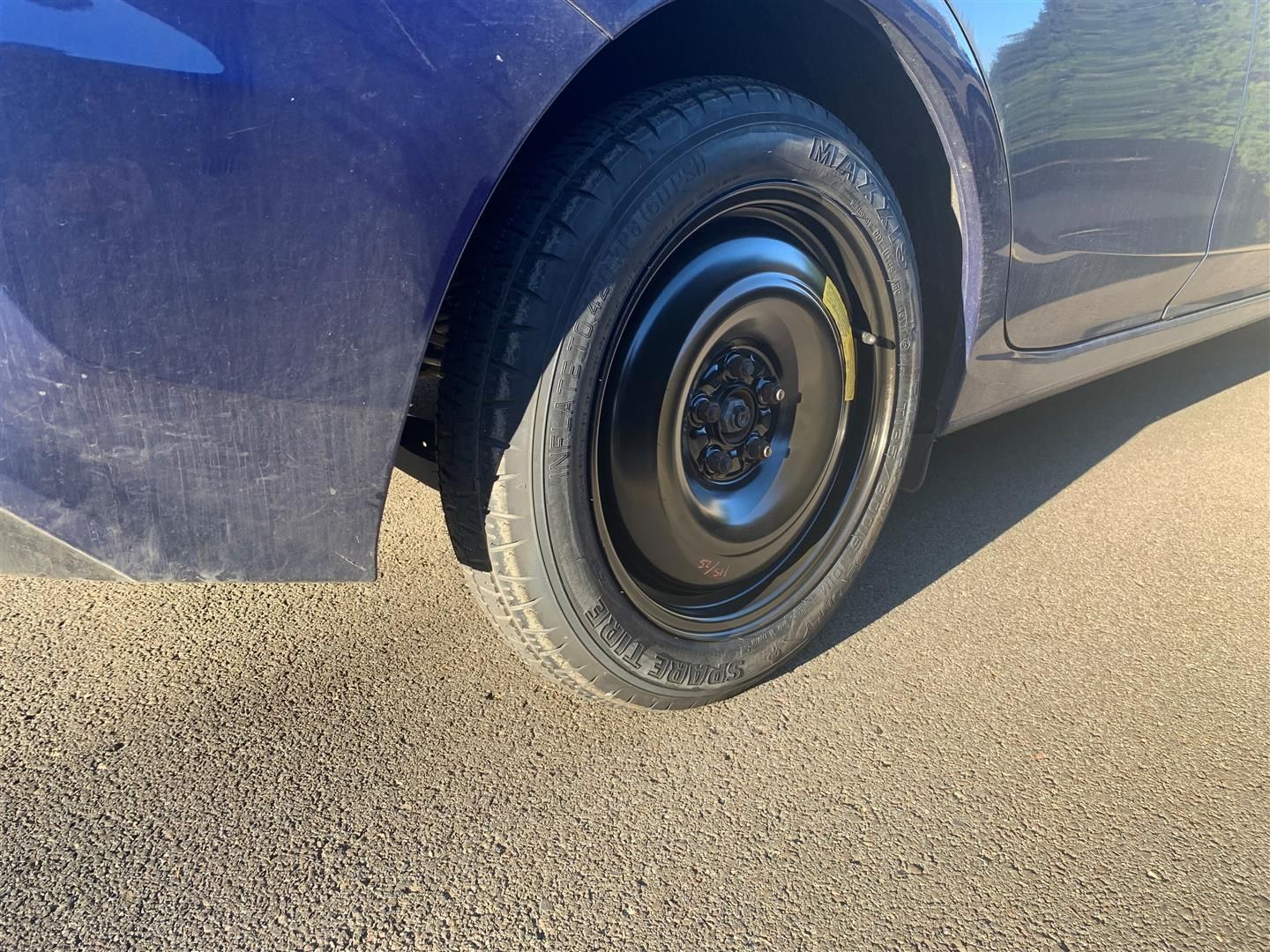 A blue car with a spare tire on it is parked on the side of the road. | Lou's Car Care Center Inc.