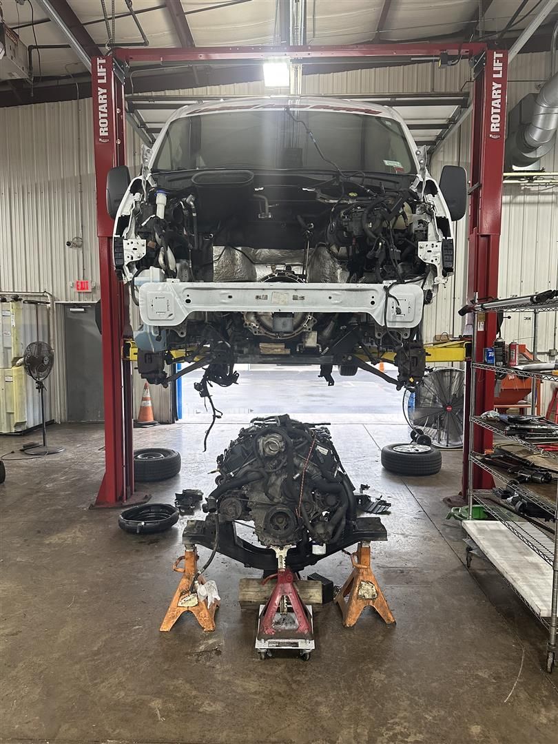 A white van is being dismantled in a garage. | Lou's Car Care Center, Inc.