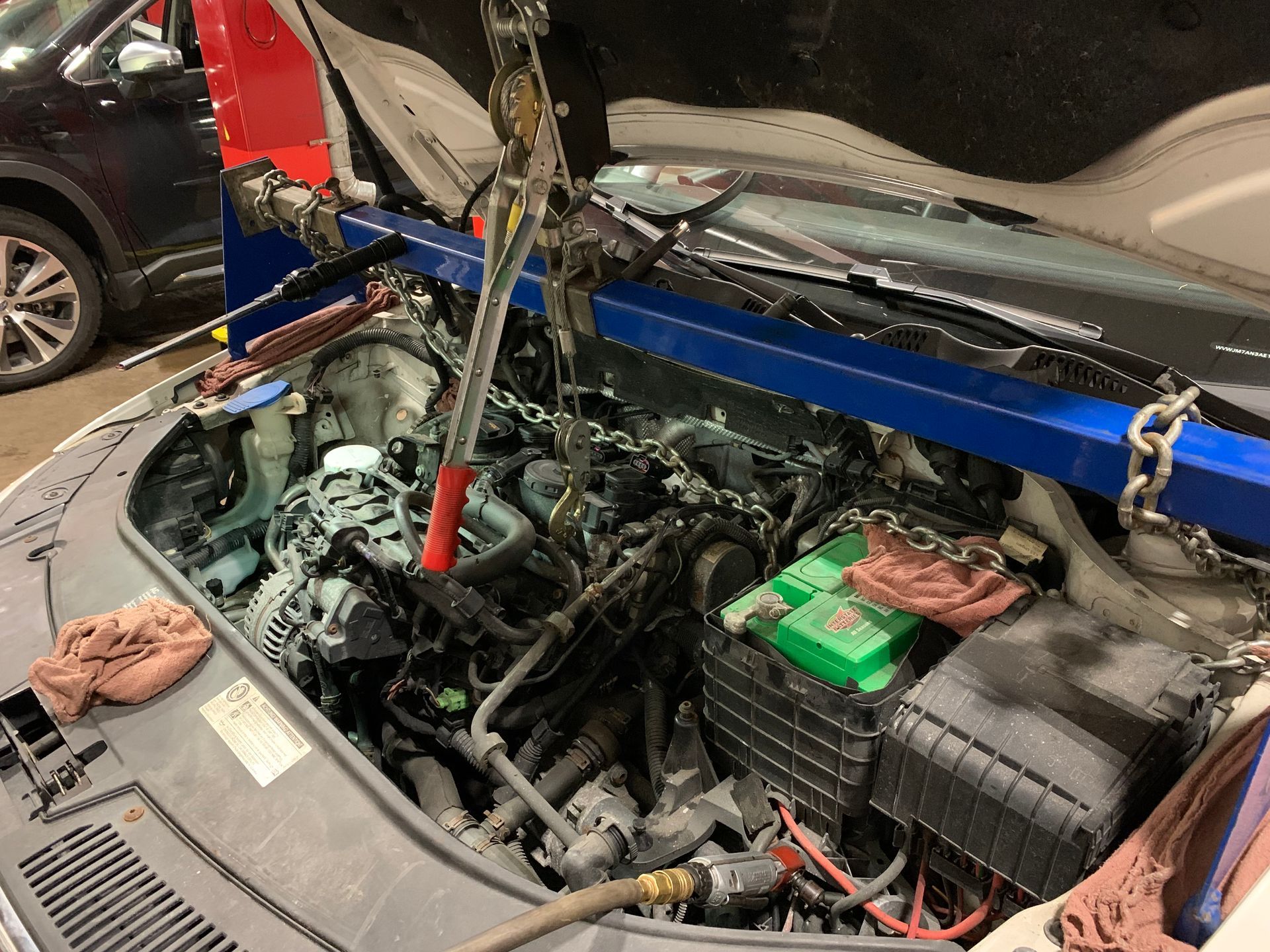 The engine of a car is being worked on in a garage. | Lou's Car Care Center, Inc.