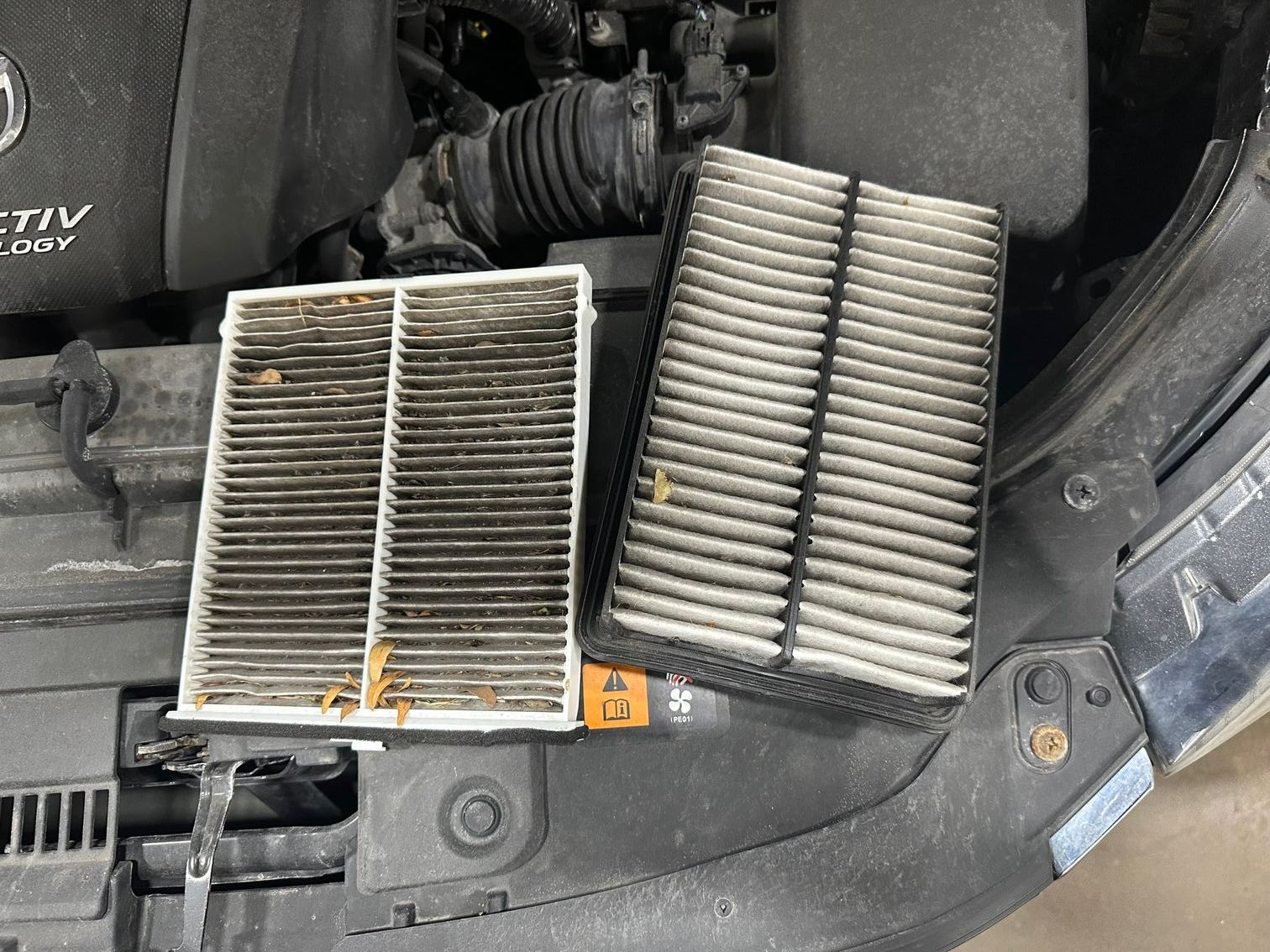 Dirty engine and cabin air filters on engine bay.