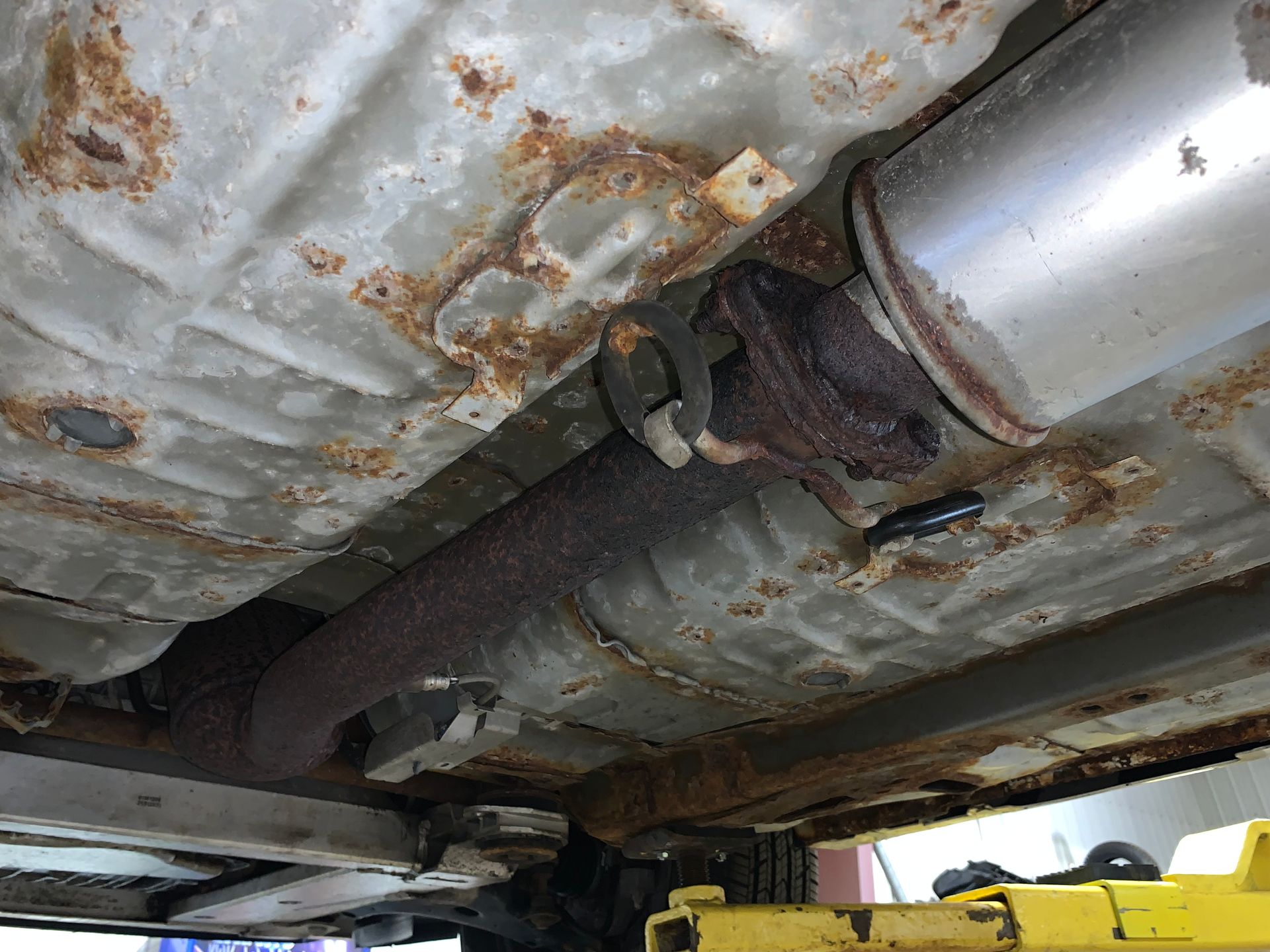 The underside of a car with a rusty exhaust pipe. | Lou's Car Care Center, Inc.