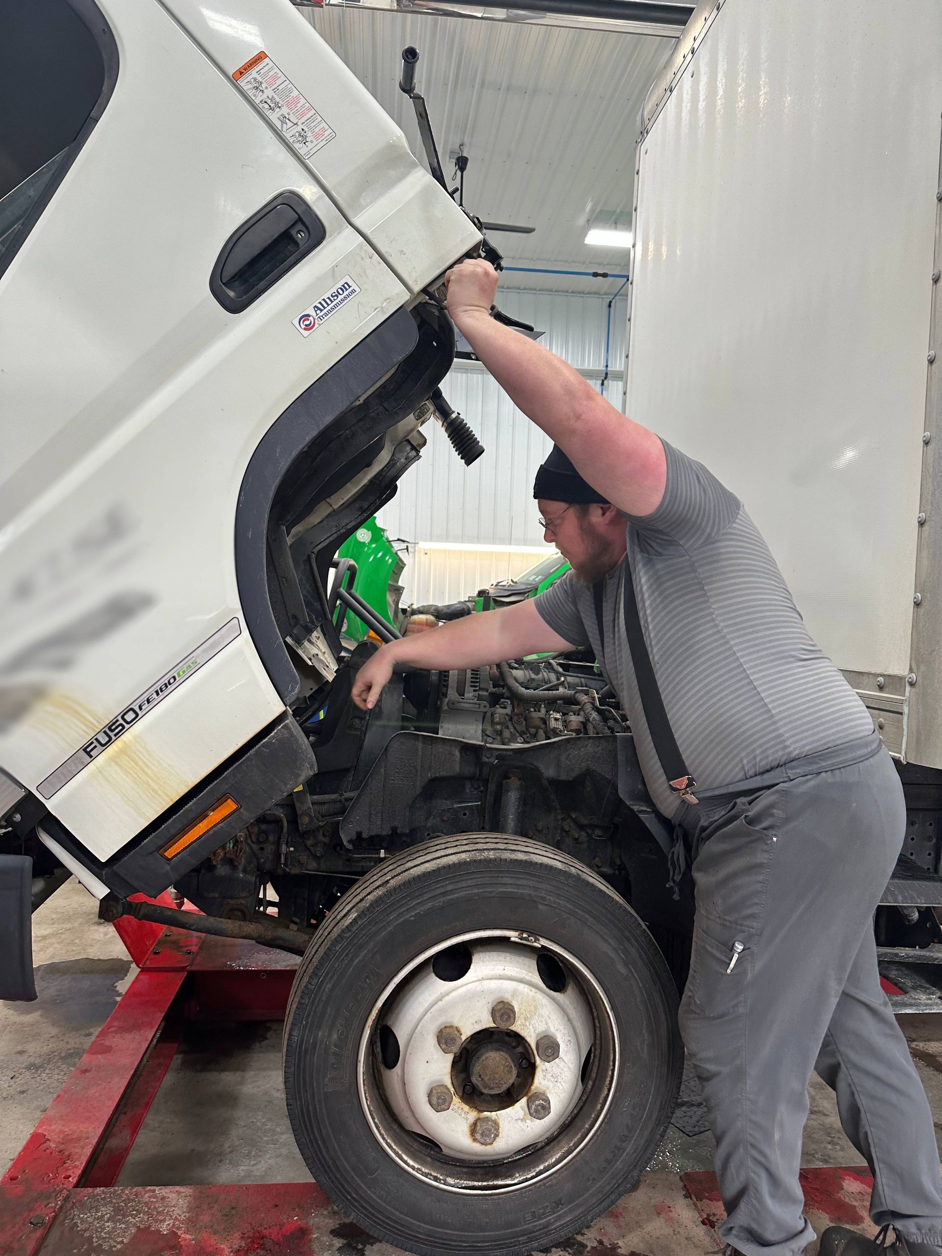 White box truck engine bay being opened by technician wearing gray clothing. | Lou's Car Care Center, Inc.