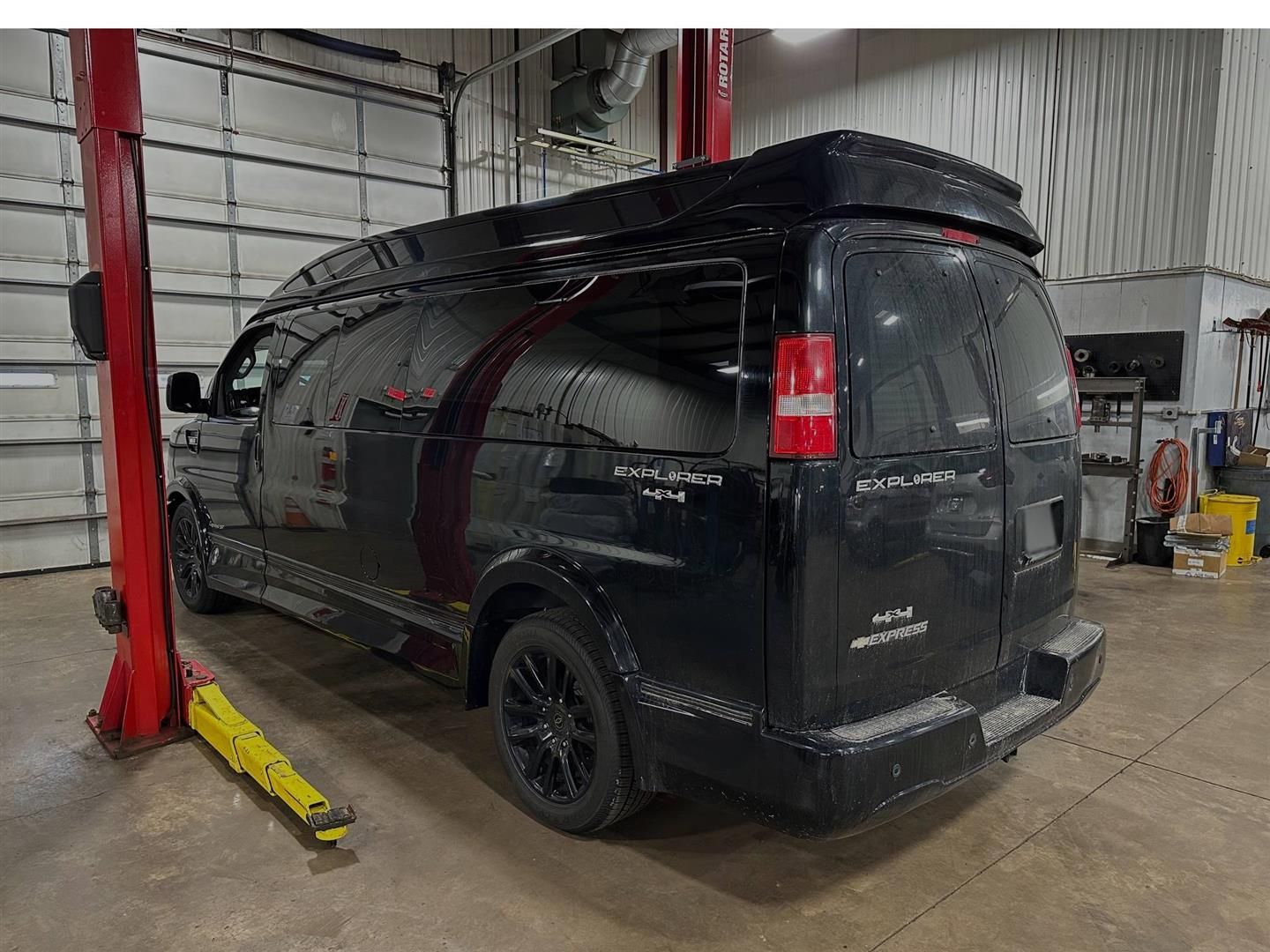 A black van is parked on a lift in a garage. | Lou's Car Care Center