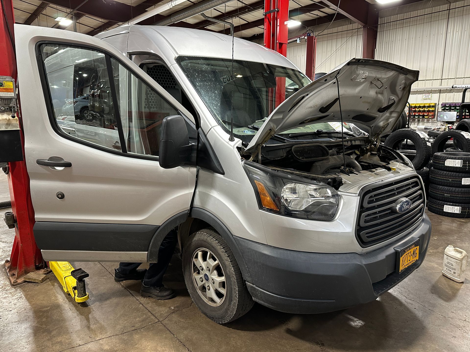 A silver van with the hood up is sitting in a garage.   | Lou's Car Care Center, Inc.