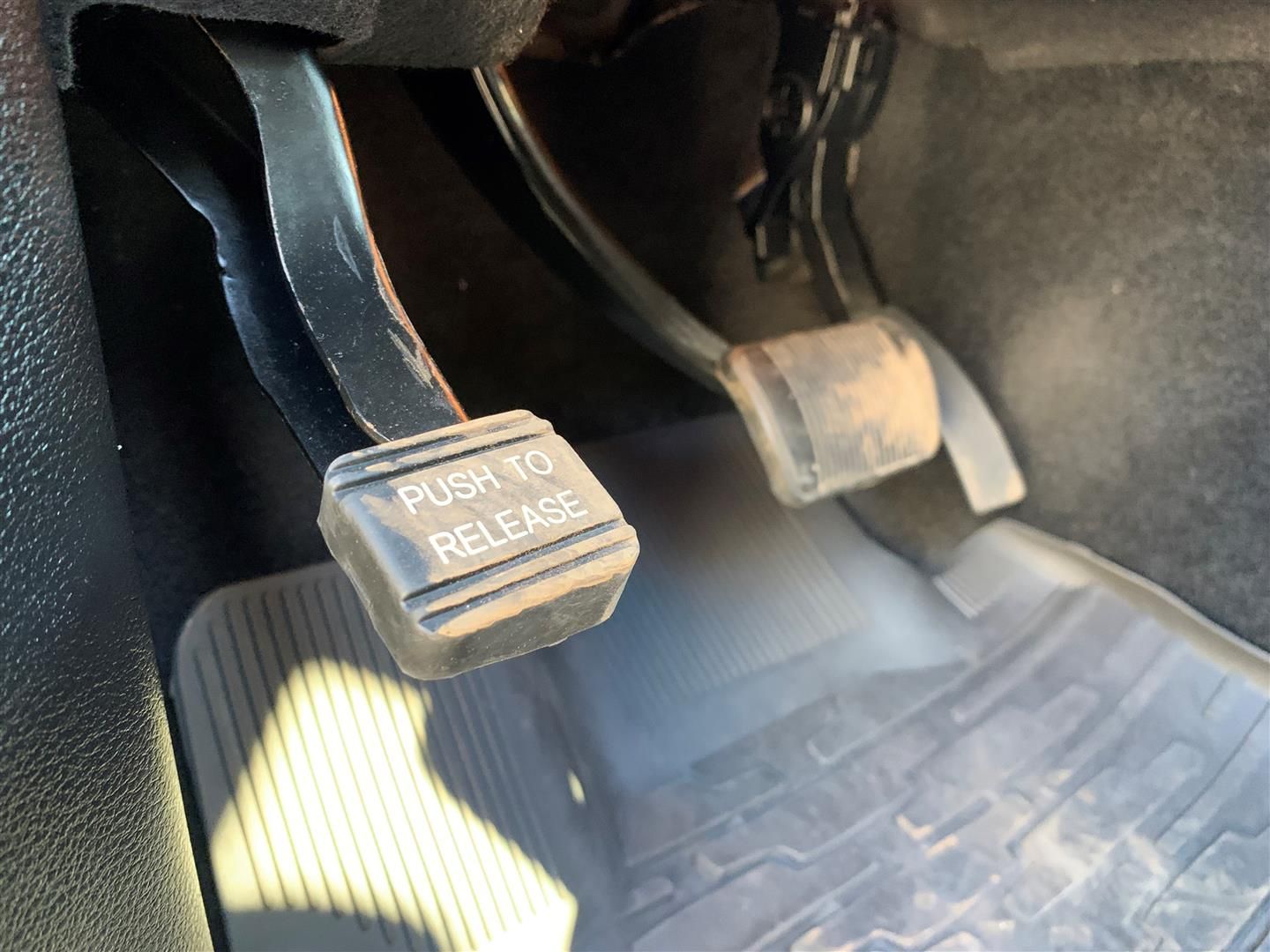 A close up of a car pedal that says push to release | Lou's Car Care Center, Inc.