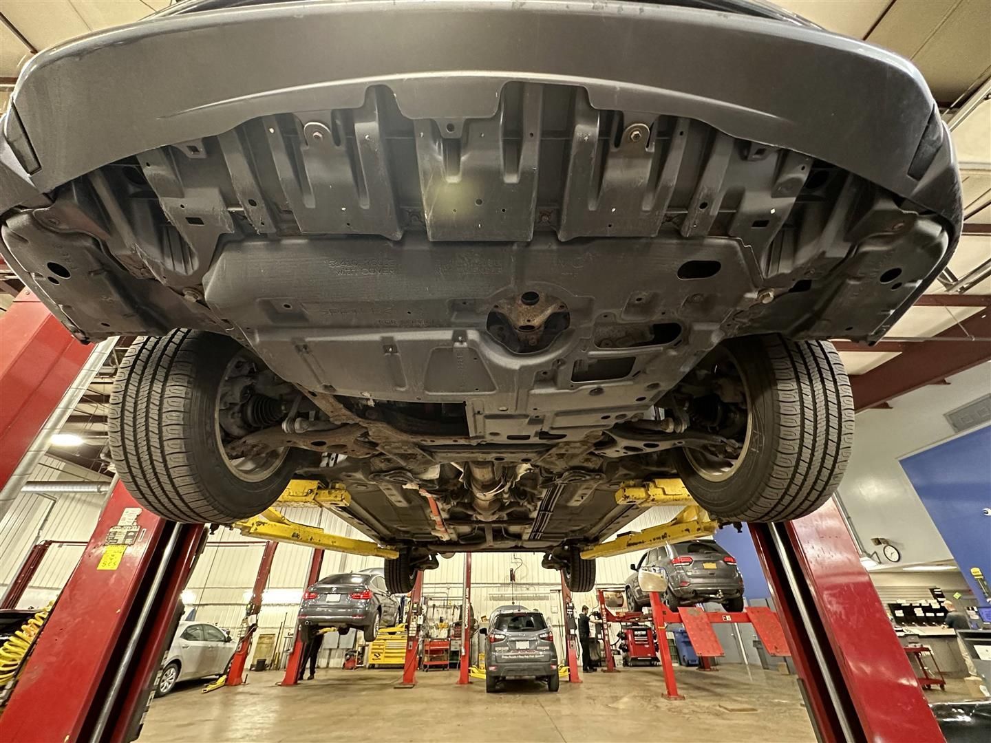 A car is sitting on a lift in a garage. | Lou's Car Care Center Inc.