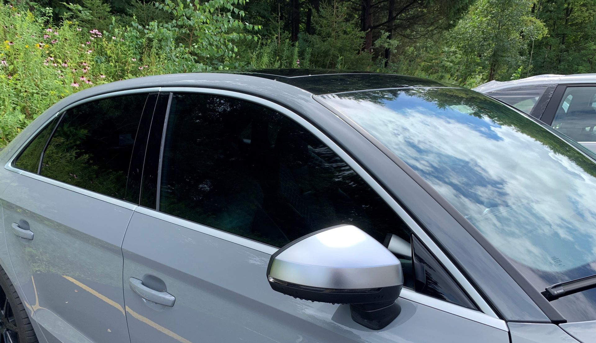 A silver car with a black roof is parked in a parking lot. | Lou's Car Care Center, Inc.