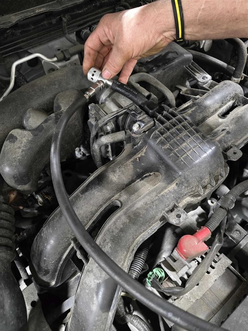 A person is working on the engine of a car.  | Lou's Car Care Center, Inc.