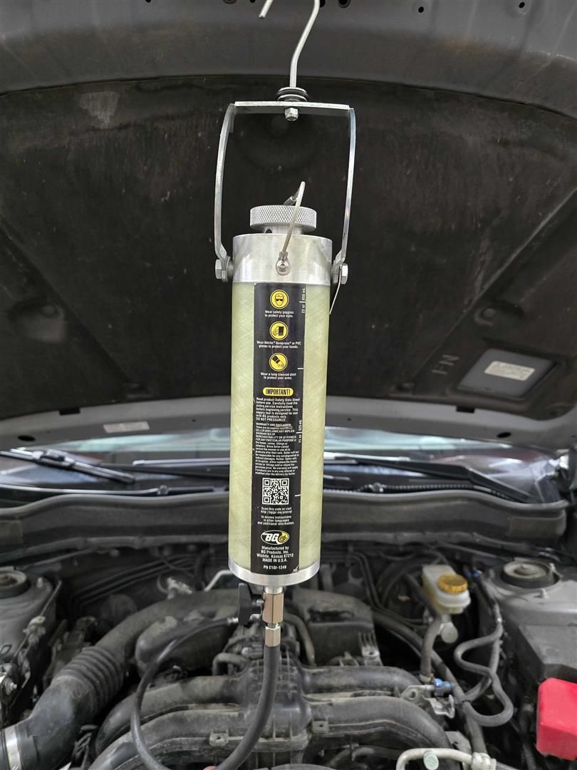 A car engine with a bottle hanging from the hood  | Lou's Car Care Center, Inc.