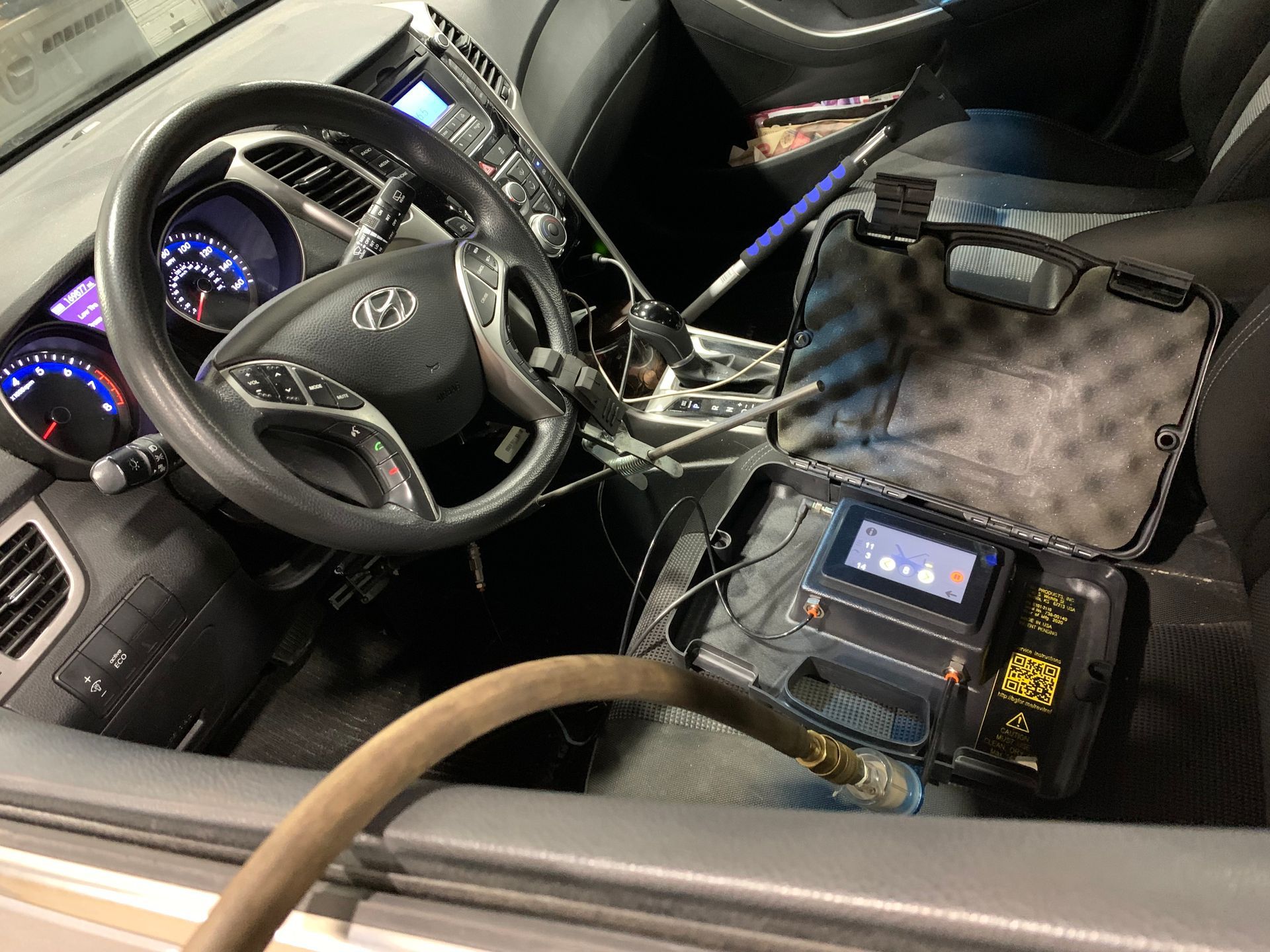 The inside of a car with a hose attached to the steering wheel. | Lou's Car Care Center, Inc.