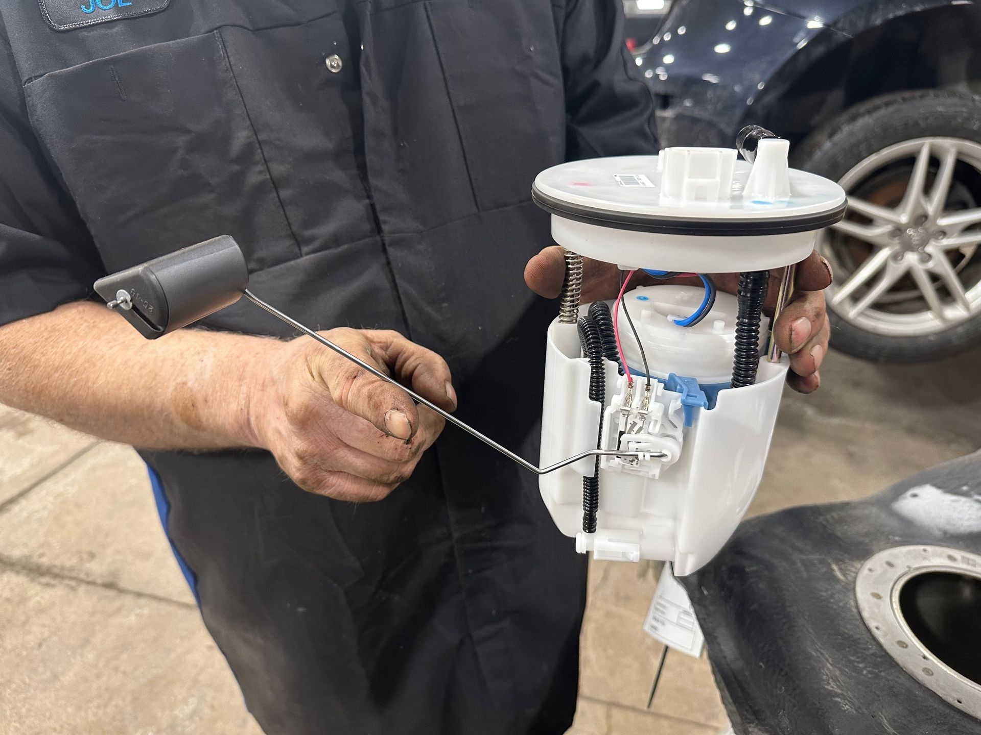New, white fuel pump being help by a technician | Lou's Car Care Center, Inc.