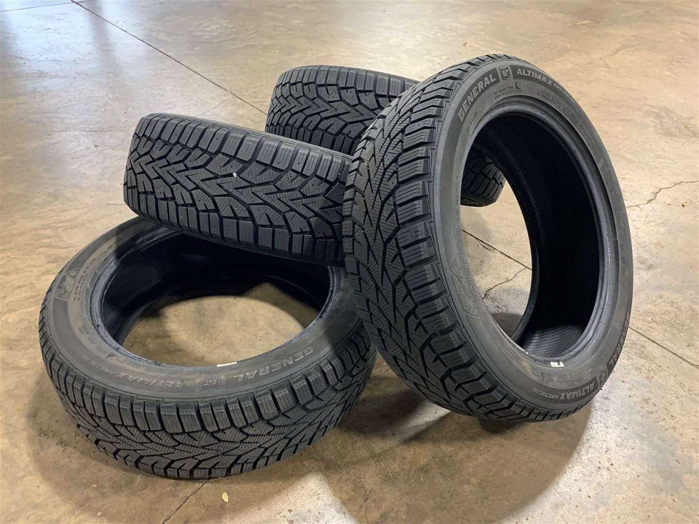 Four tires are stacked on top of each other on a concrete floor. | Lou's Car Care Center, Inc.