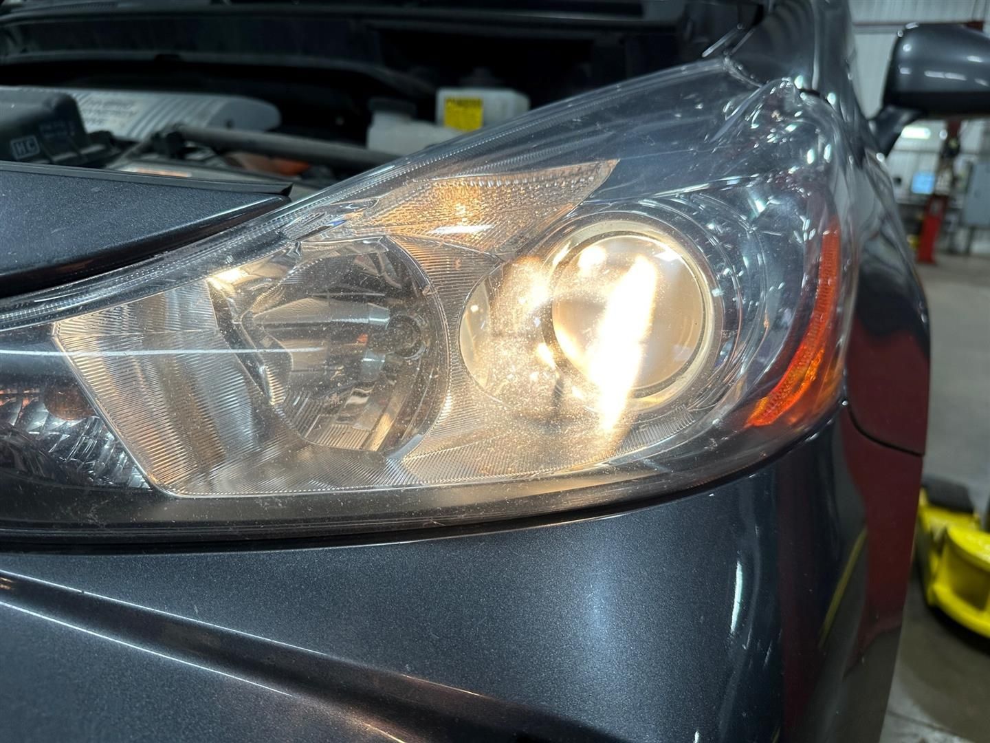 A close up of a car headlight with the hood open | Lou's Car Care Center, Inc.