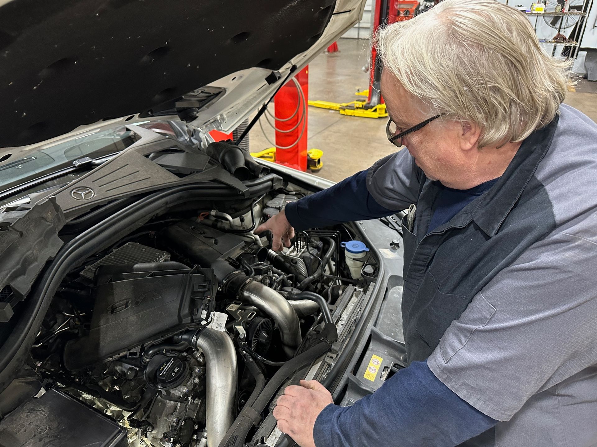 A man is working under the hood of a car. | Lou's Car Care Center, Inc.