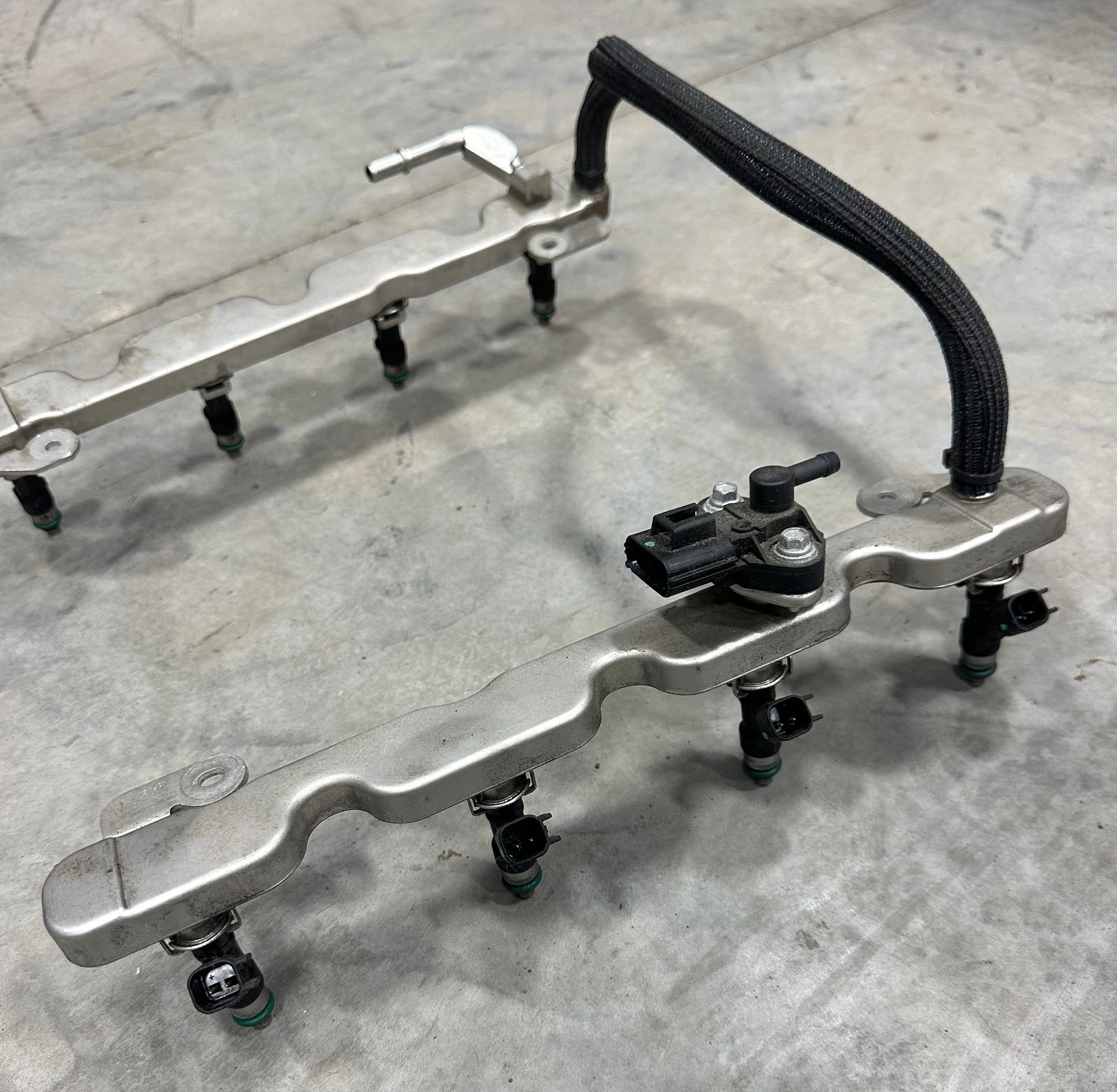 Fuel injectors for a vehicle on the cement shop floor.