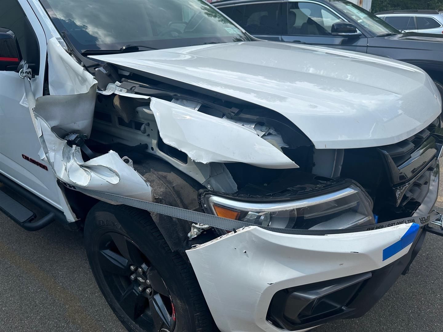 A white truck with a damaged front end is parked on the side of the road. |   | Lou's Car Care Center, Inc.