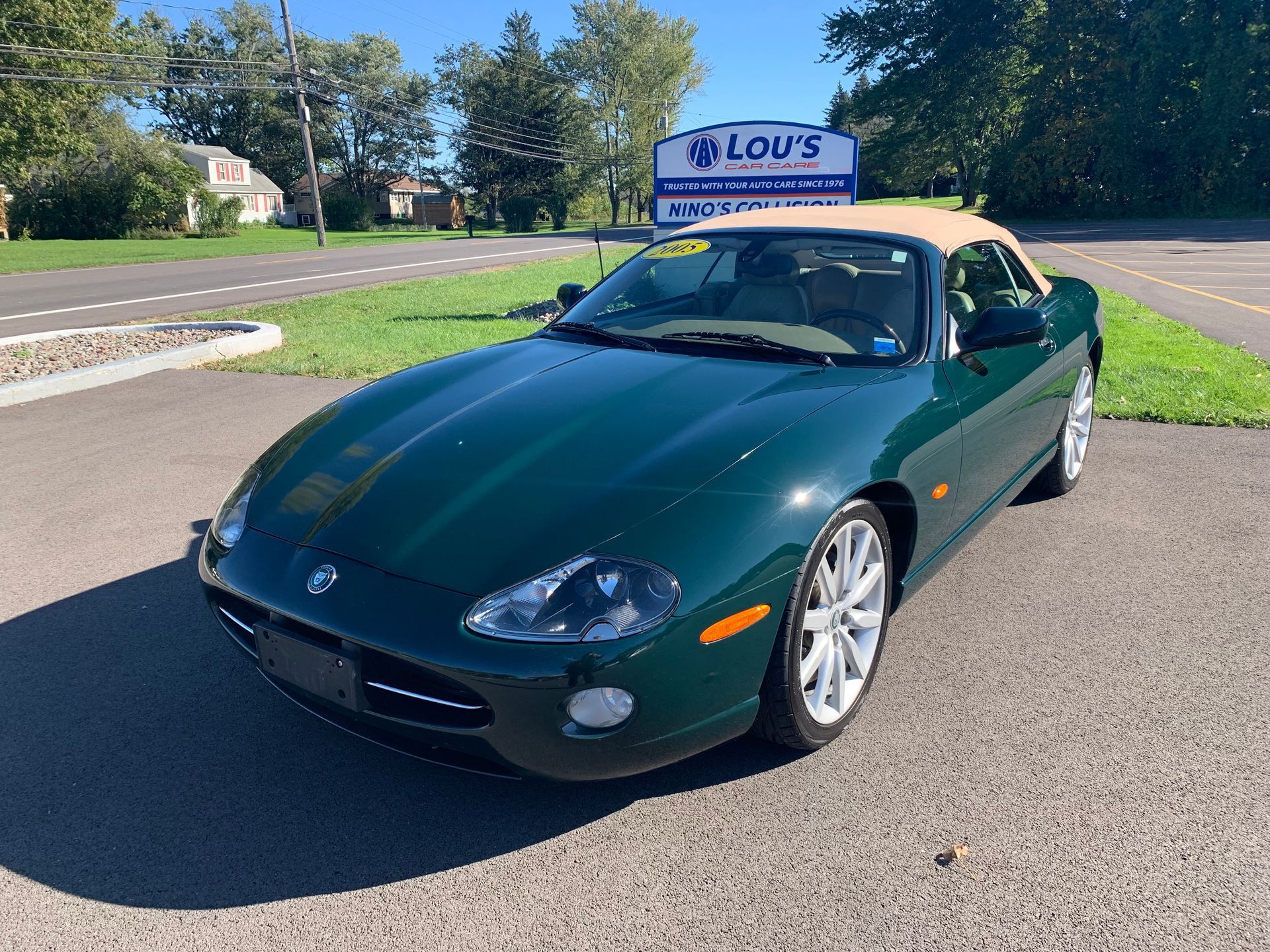 A green sports car is parked in front of a lou 's sign. | Lou's Car Care Center, Inc.