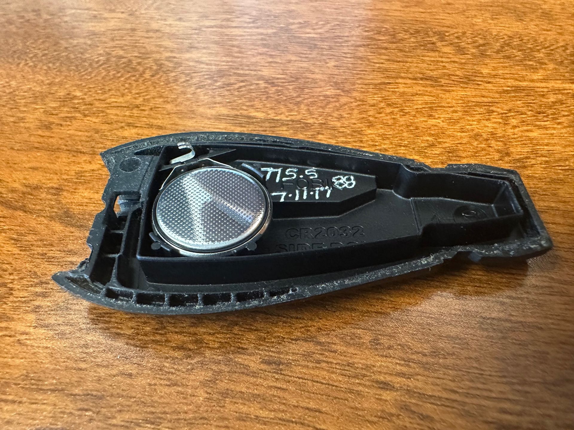 Black Jeep key fob battery on wooden desk.