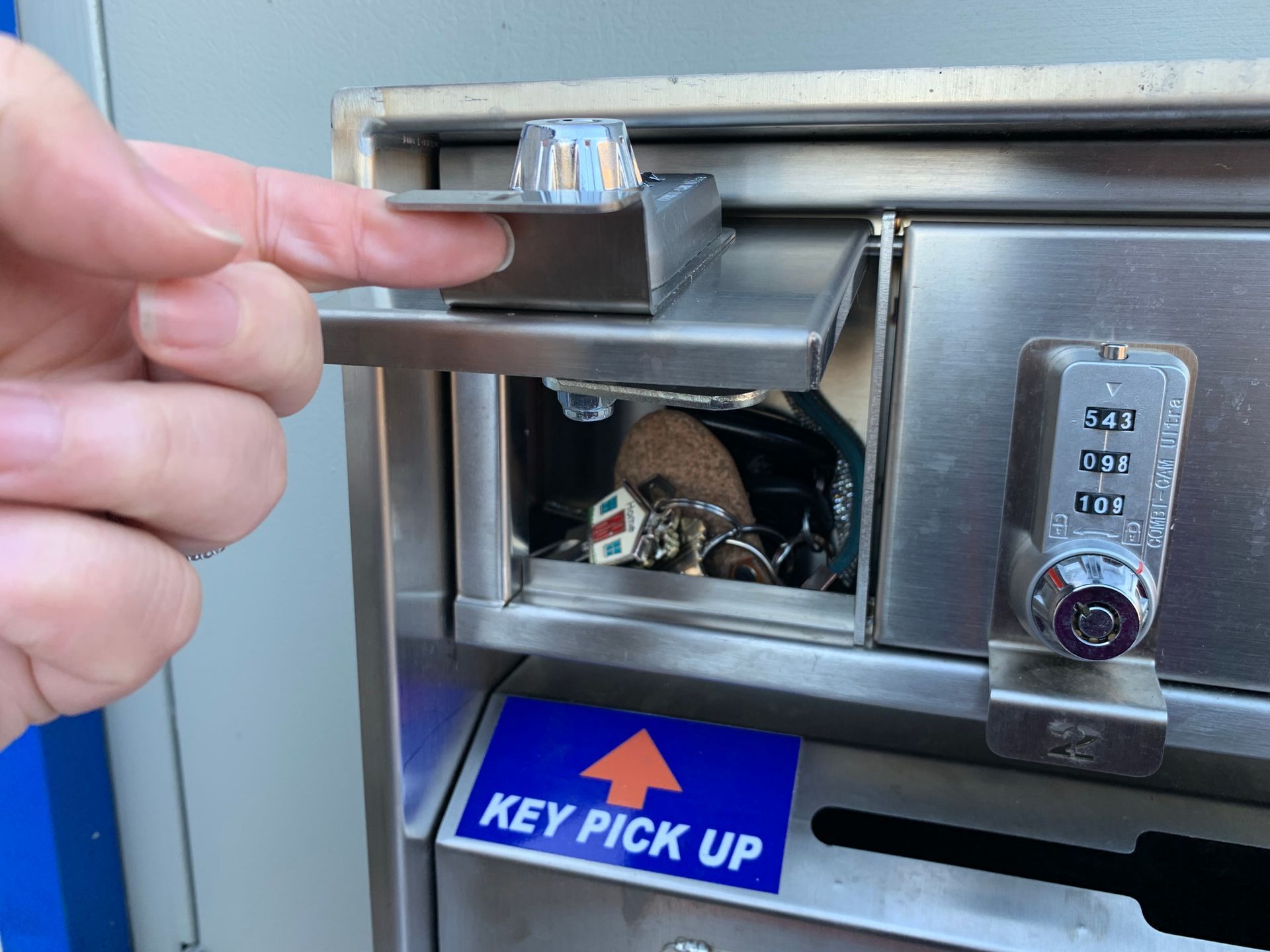 A person is picking up keys from a key pick up box | Lou's Car Care Center Inc.