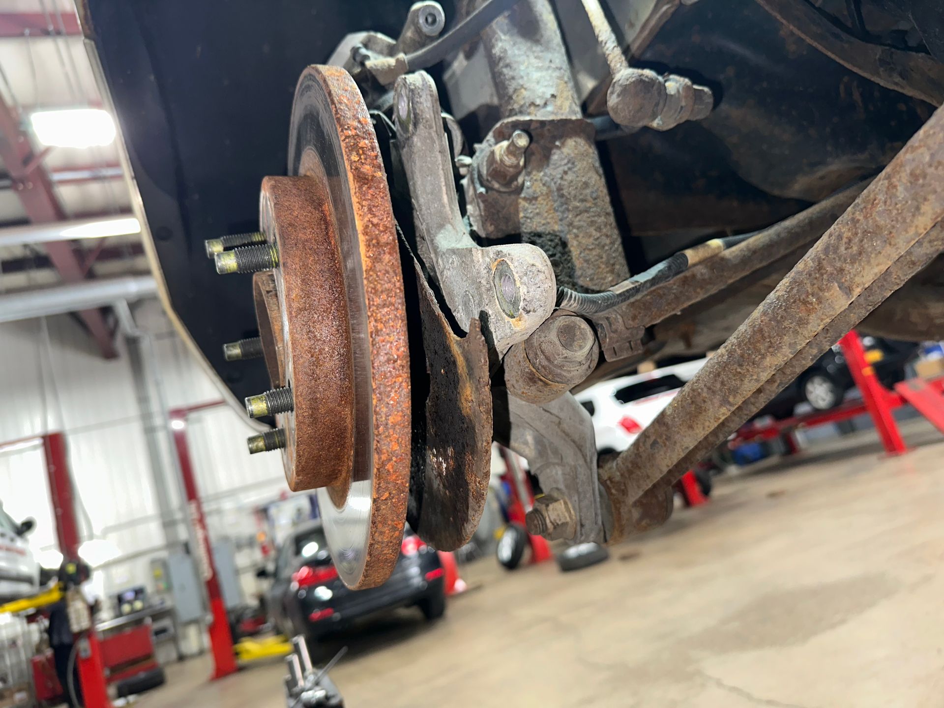 A close up of a brake disc on a car in a garage. | Lou's Car Care Center Inc.