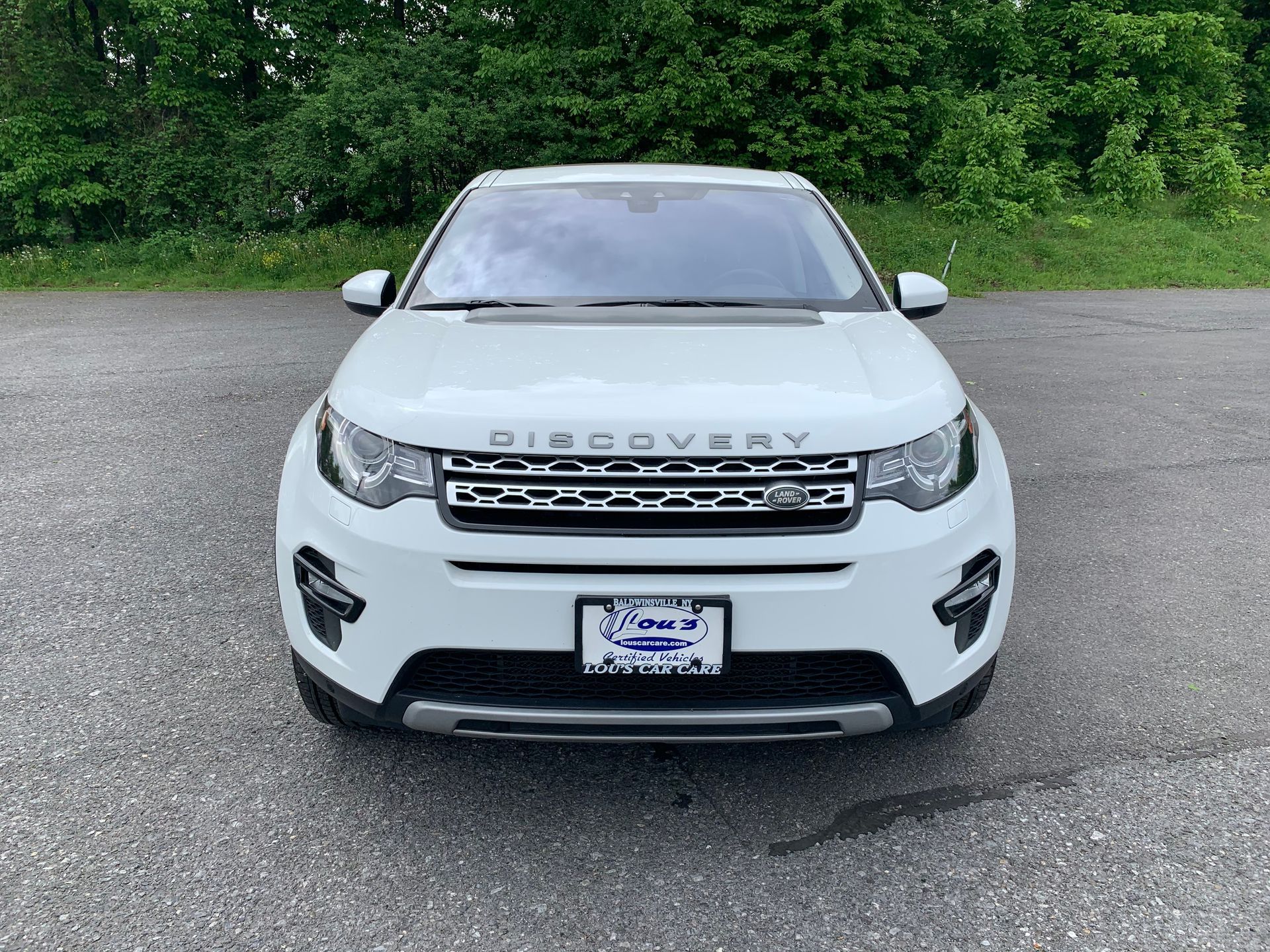 A white land rover discovery sport is parked in a parking lot. | Lou's Car Care Center Inc.