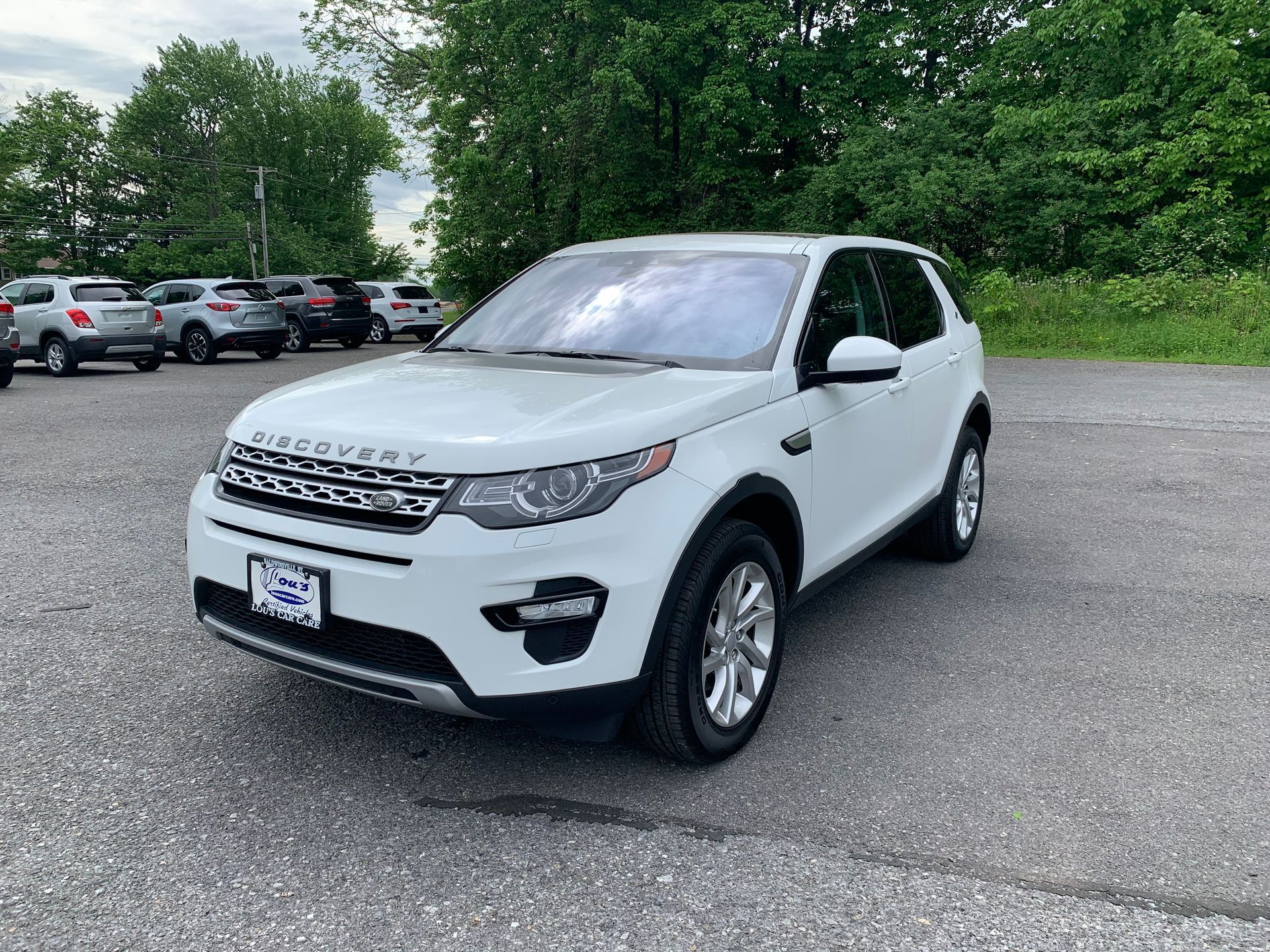 A white land rover discovery sport is parked in a parking lot. | Lou's Car Care Center, Inc.