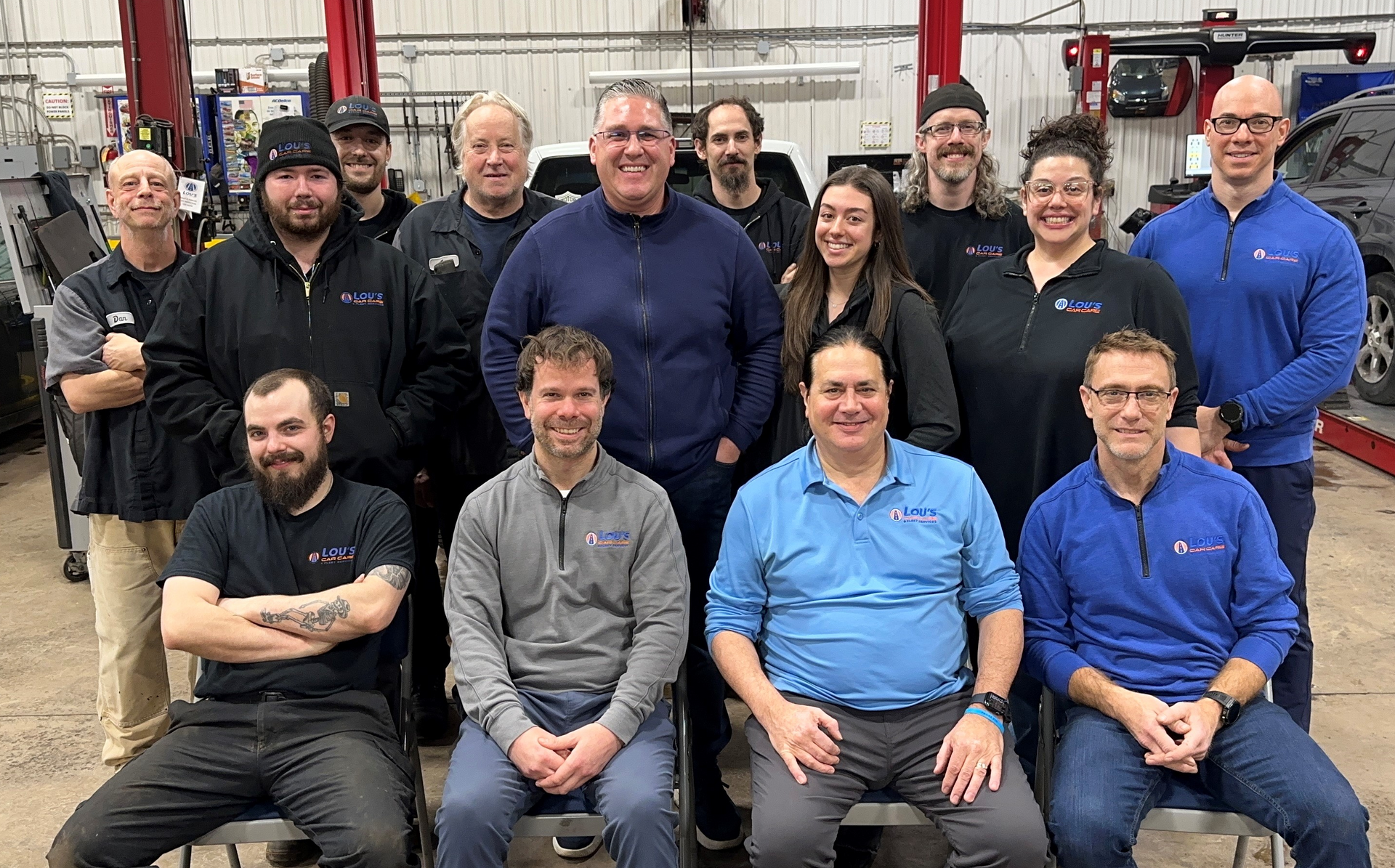 A group of people are posing for a picture in a garage. | Lou's Car Care Center