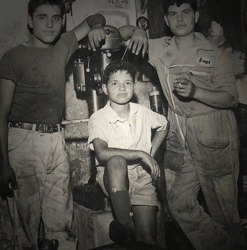 A black and white photo of a boy sitting with two men | Lou's Car Care