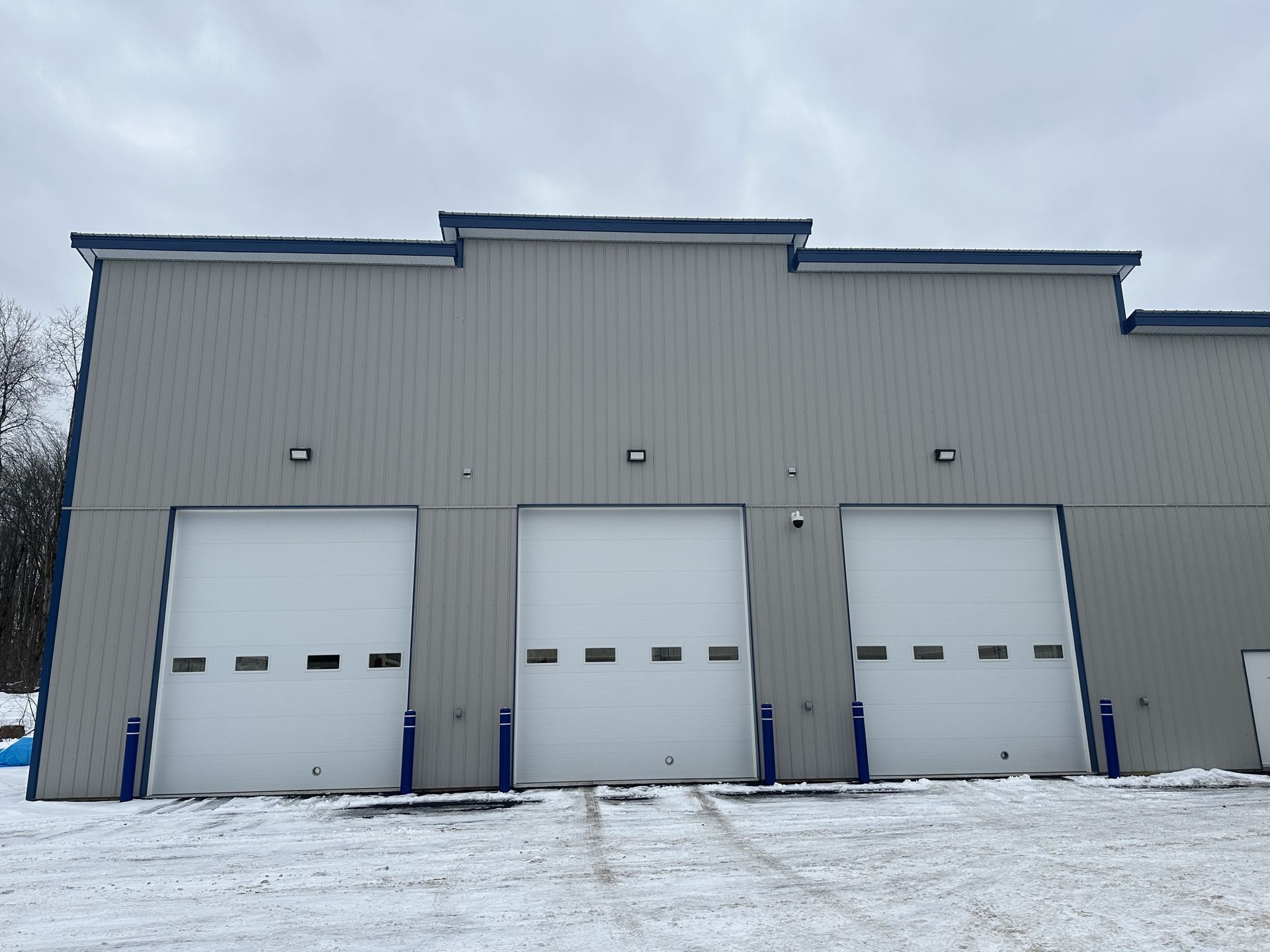 Gray fleet center building with three, white bay doors with snow of the ground | Lou's Car Care Center, Inc.