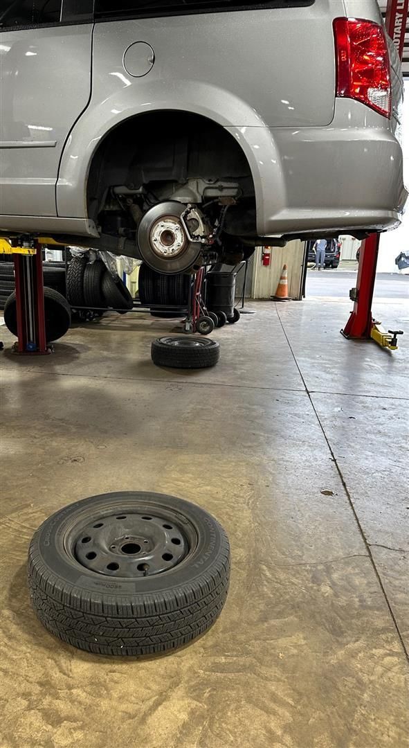 A car is being repaired in a garage with a spare tire on the floor. | Lou's Car Care Center, Inc.