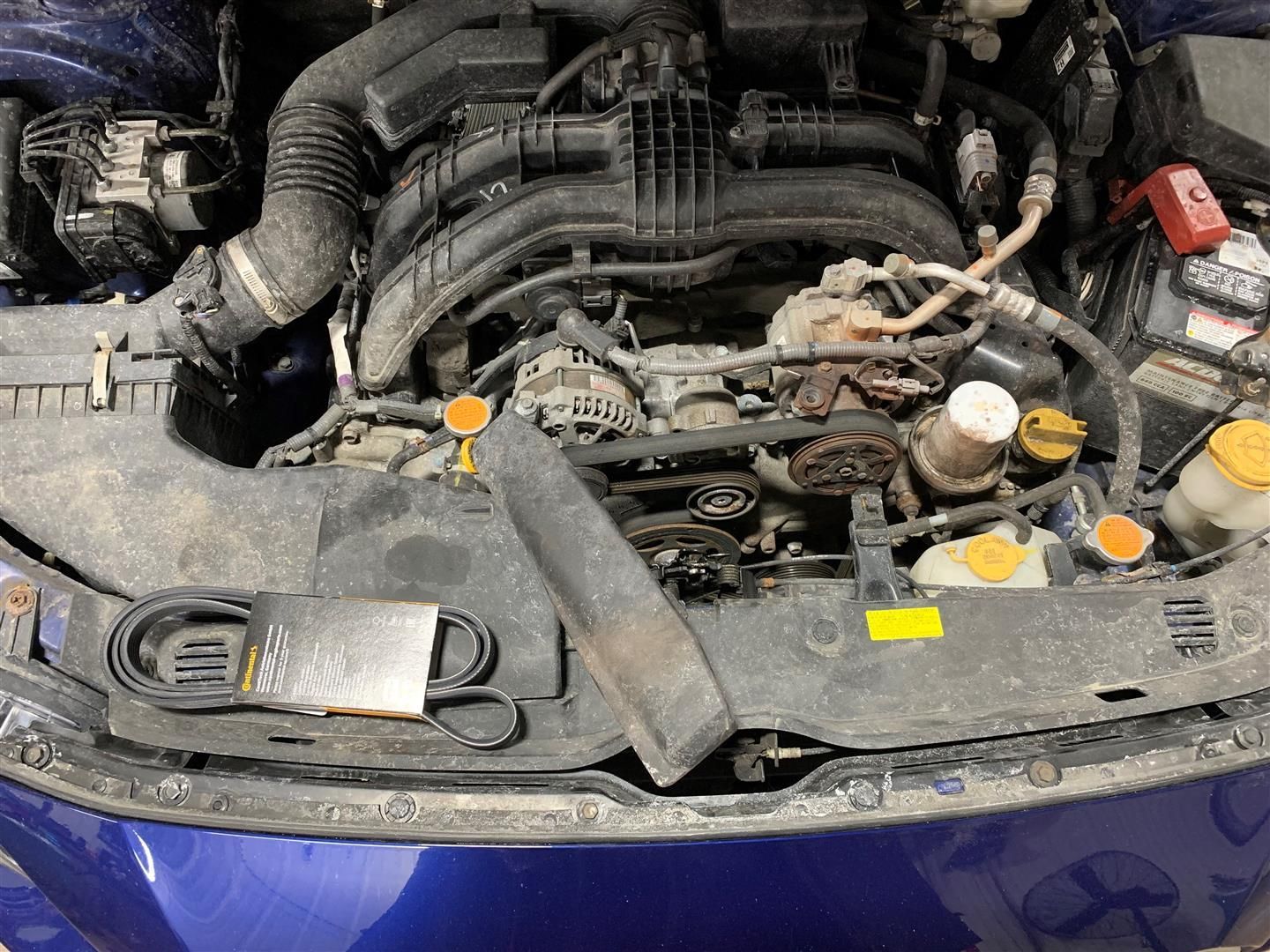 The engine of a blue car is visible under the hood. | Lou's Car Care Center Inc.