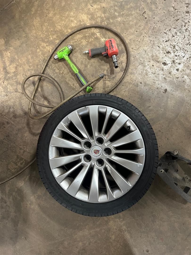 A tire is sitting on the ground next to a tool.  | Lou's Car Care Center, Inc.