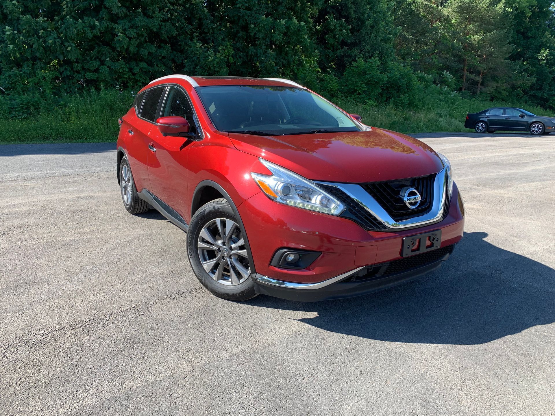 A red nissan murano is parked in a parking lot. | Lou's Car Care Center, Inc.