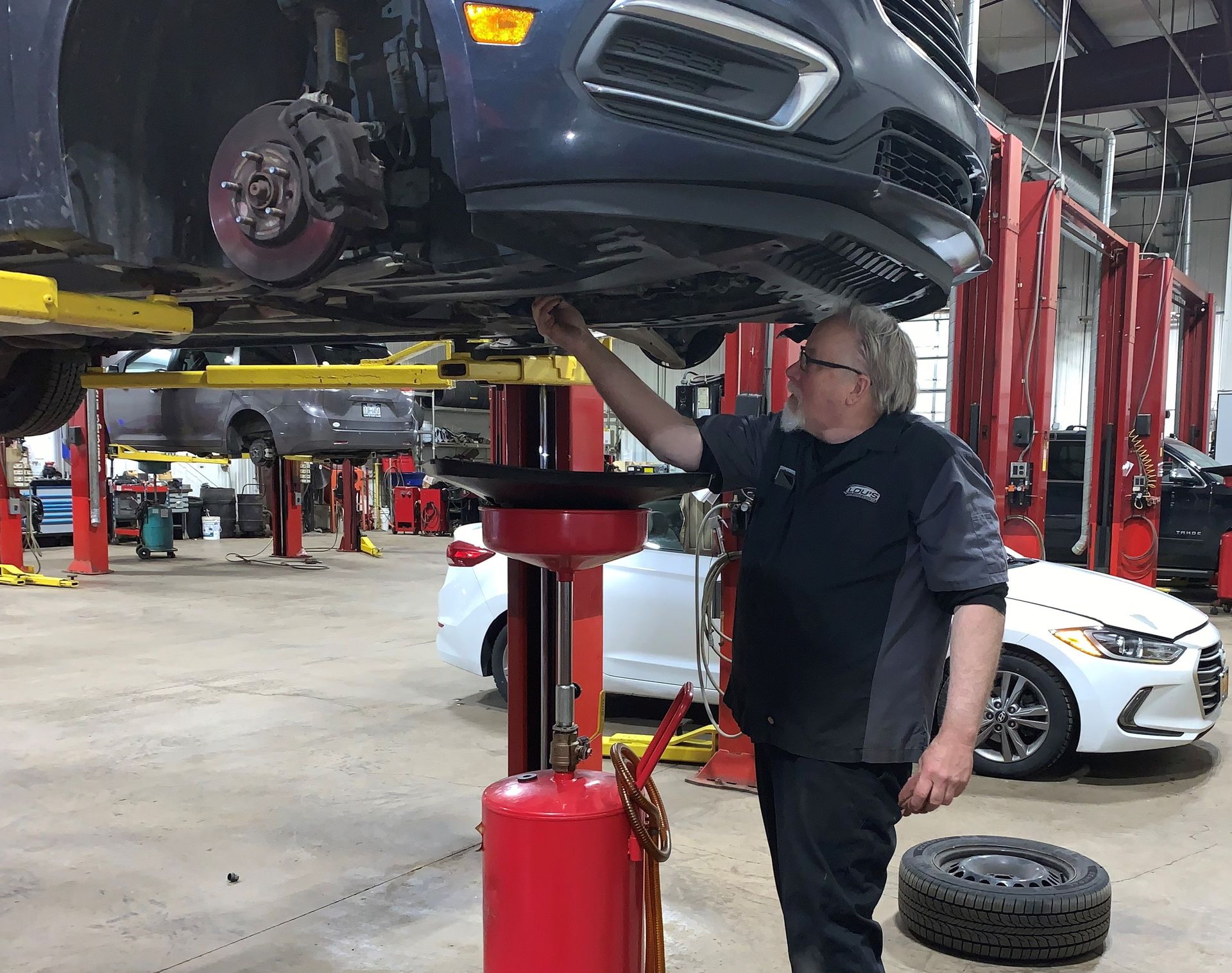 A man is working on a car in a garage. | Lou's Car Care Center, Inc.