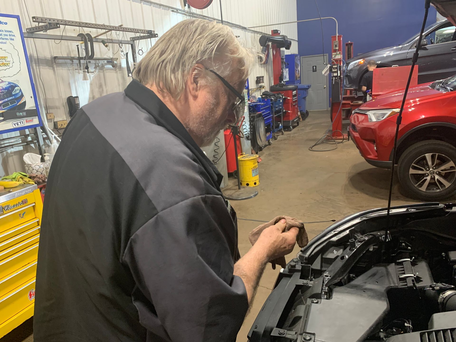 A man is working on the engine of a car in a garage. | Lou's Car Care Center, Inc.