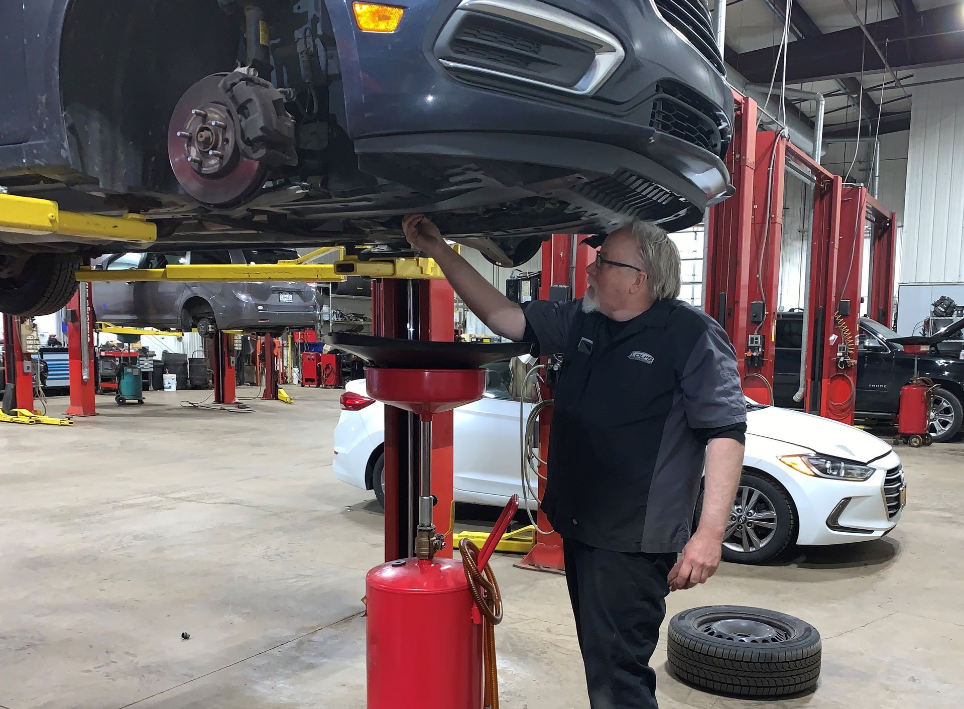 A man is working on a car in a garage. | Lou's Car Care Center, Inc.