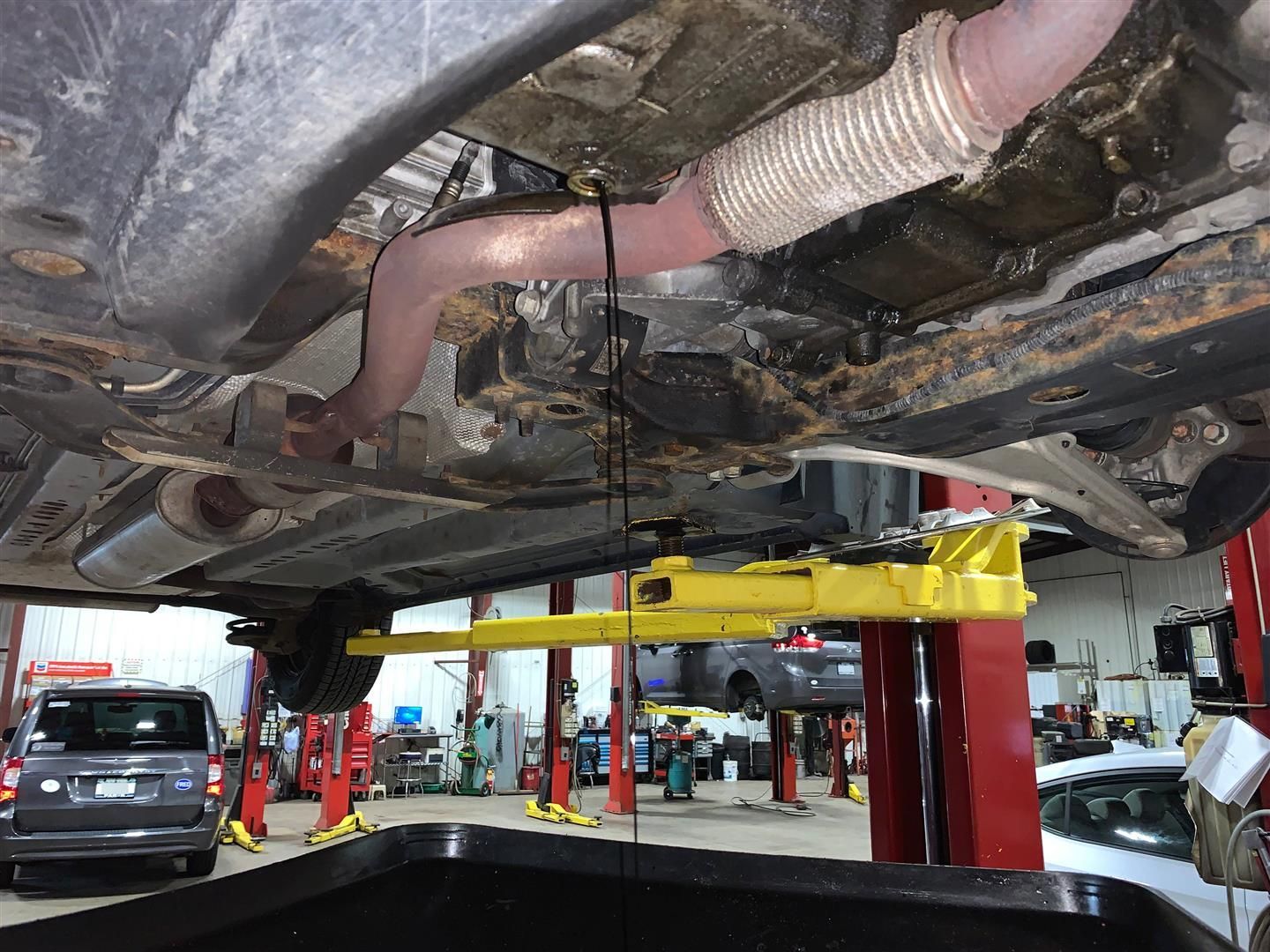 A car is sitting on a lift in a garage. | Lou's Car Care Center Inc.