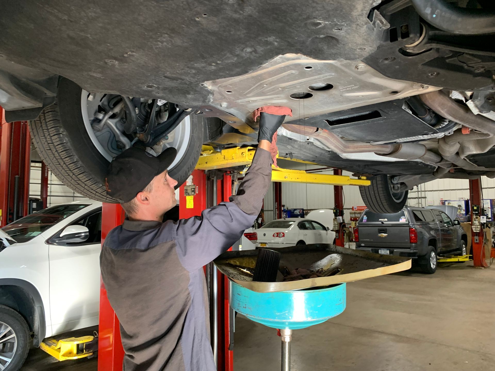 A man is working under a car in a garage. | Lou's Car Care Center, Inc.