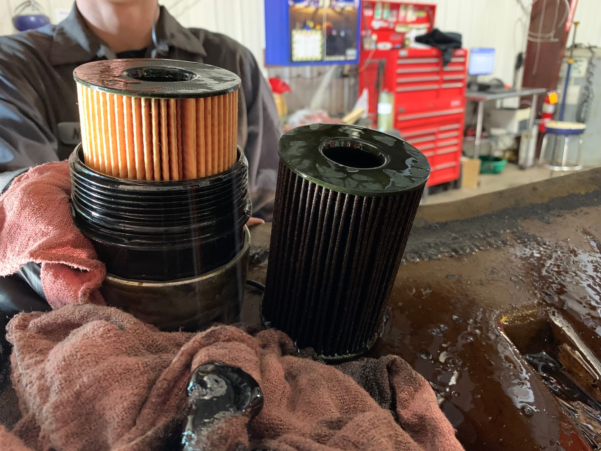 A man is holding two dirty oil filters in his hands. | Lou's Car Care Center, Inc.
