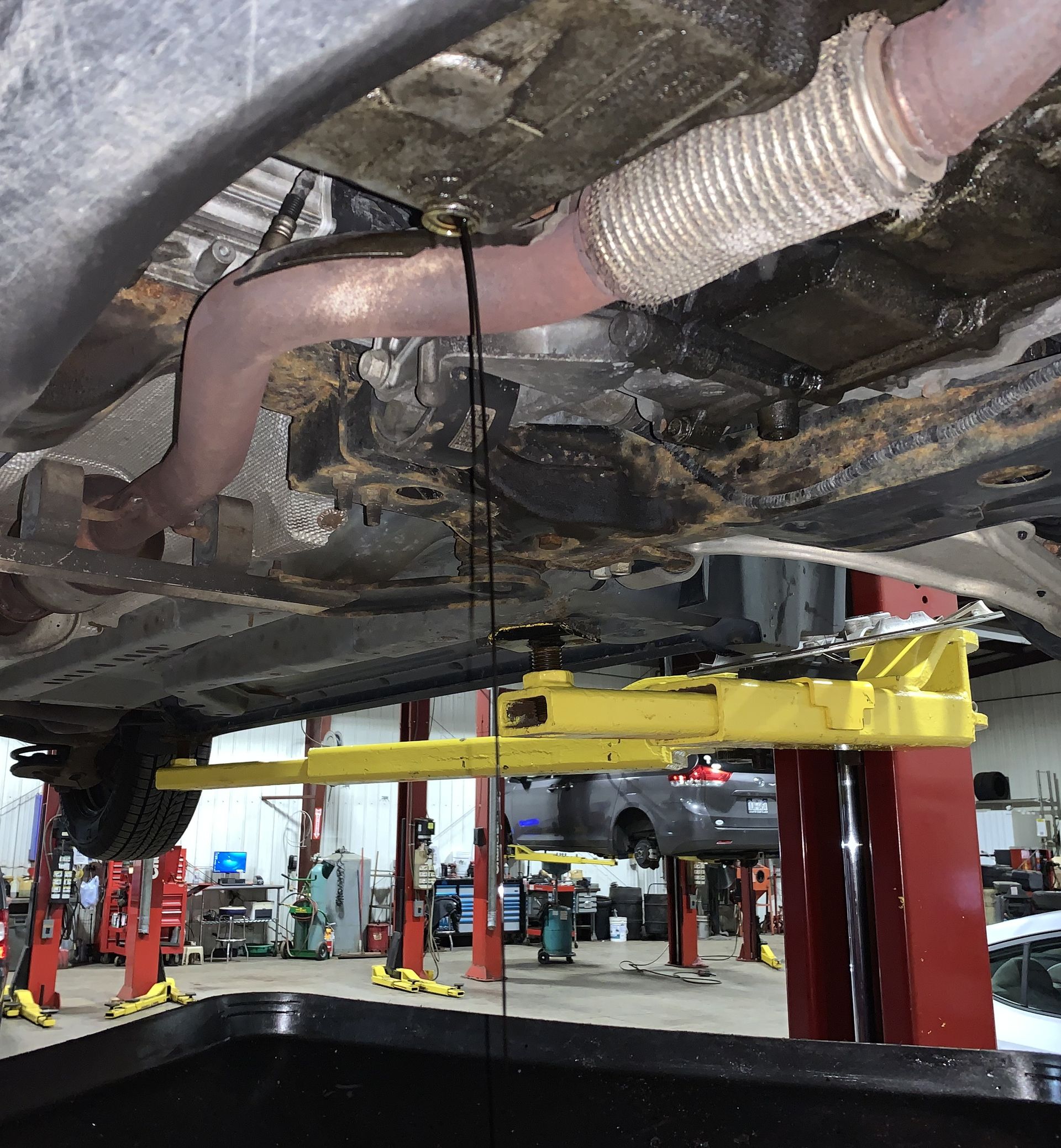 Old motor oil draining from vehicle during oil change service.