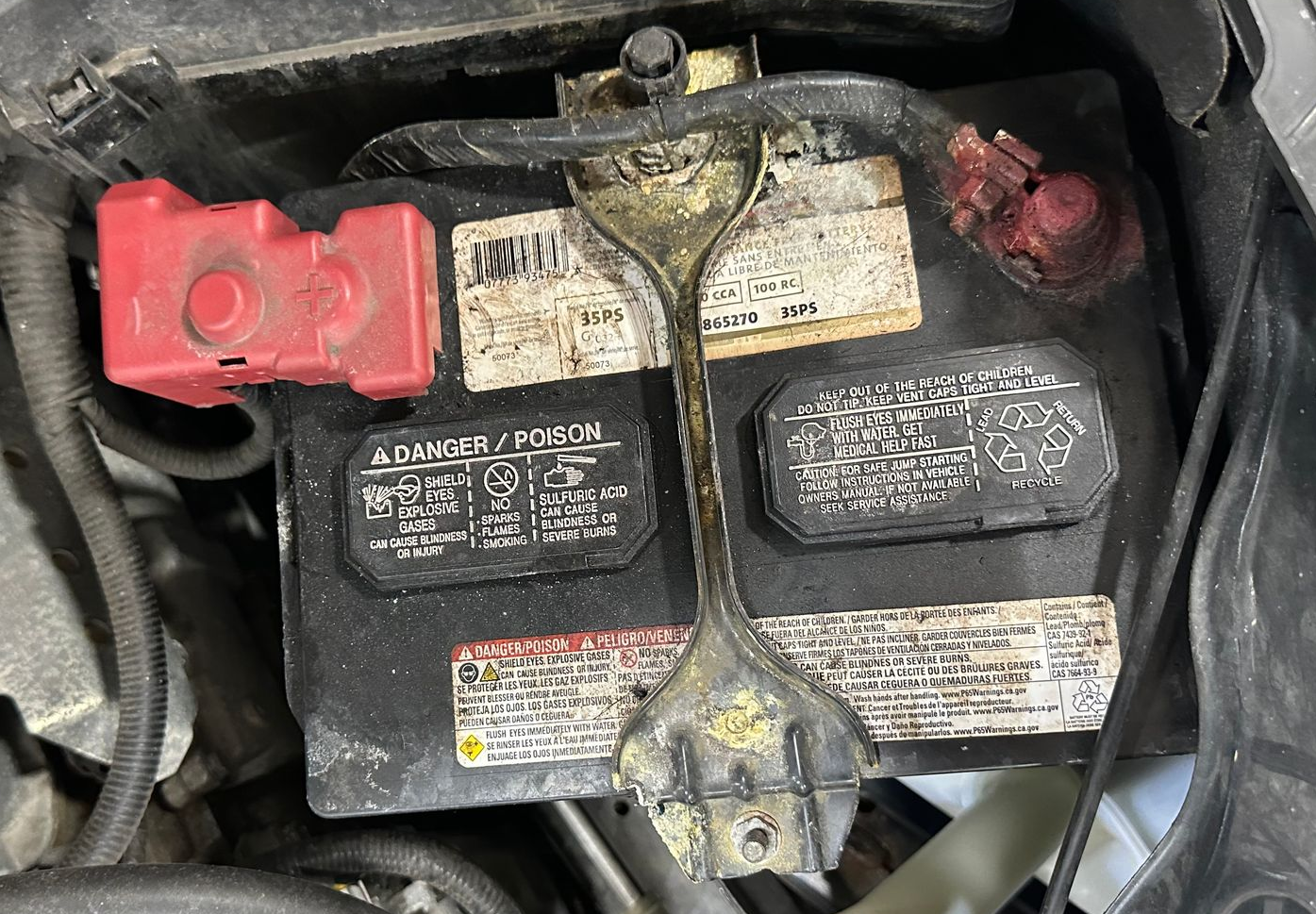 Old car battery in vehicle engine bay area.