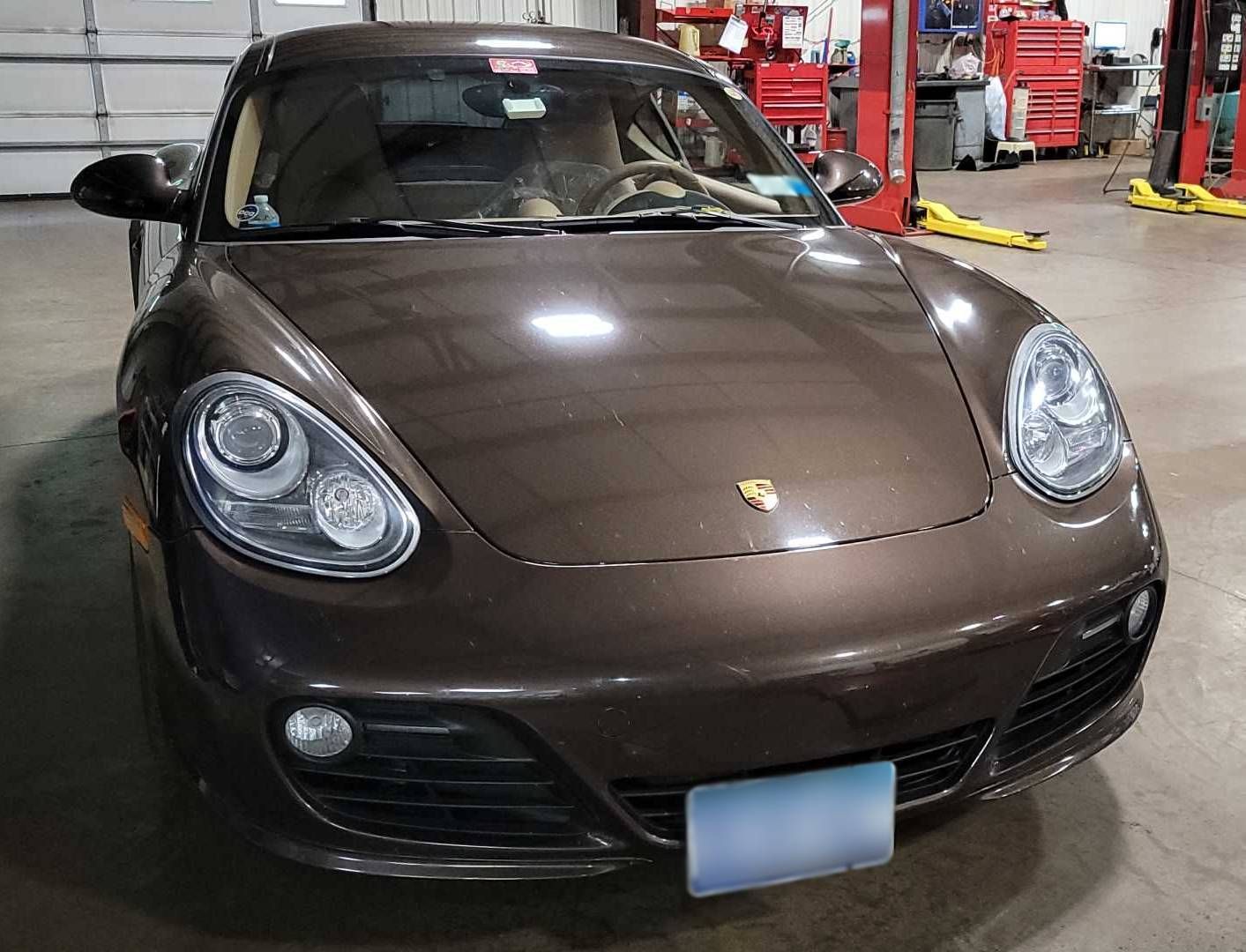 A brown porsche boxster is parked in a garage. | Lou's Car Care Center, Inc.