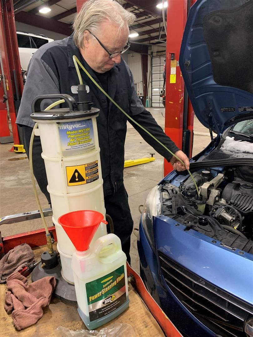 A man is working on a blue car in a garage. | Lou's Car Care Center Inc.