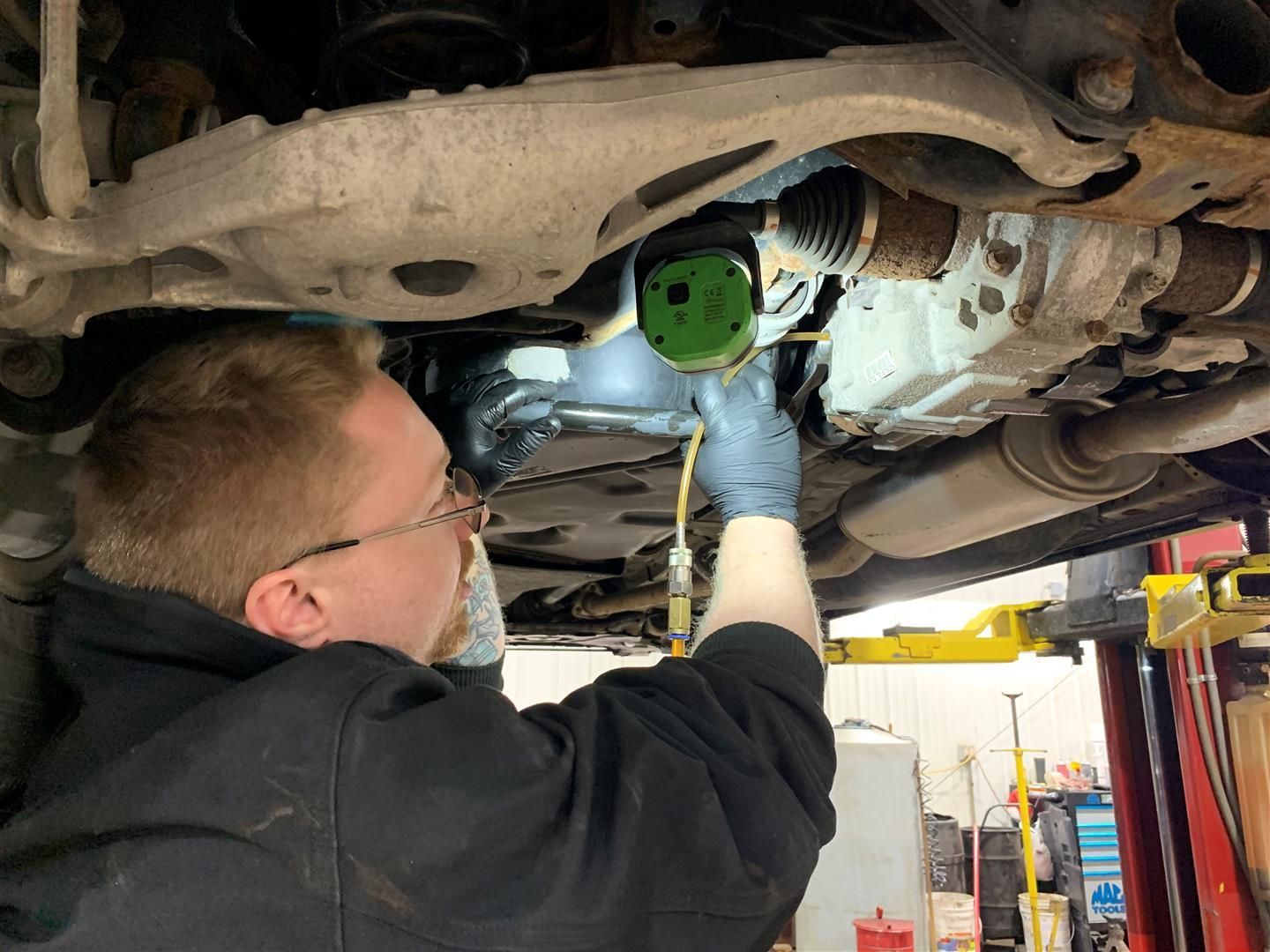 A man is working under a car in a garage. | Lou's Car Care Center Inc.