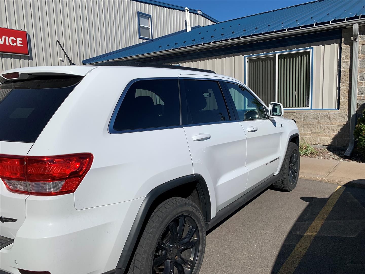 A white jeep grand cherokee is parked in front of a building. | Lou's Car Care Center, Inc.