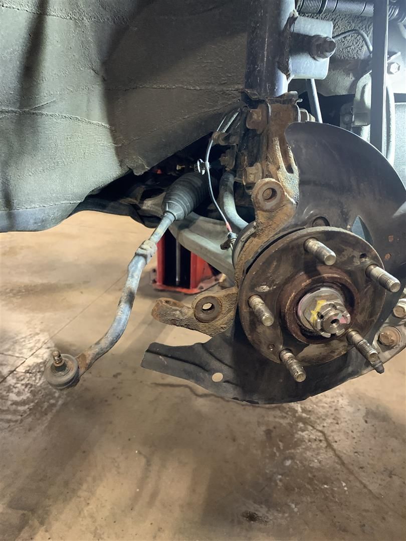 A close up of a wheel on a car in a garage. | Lou's Car Care Center, Inc.