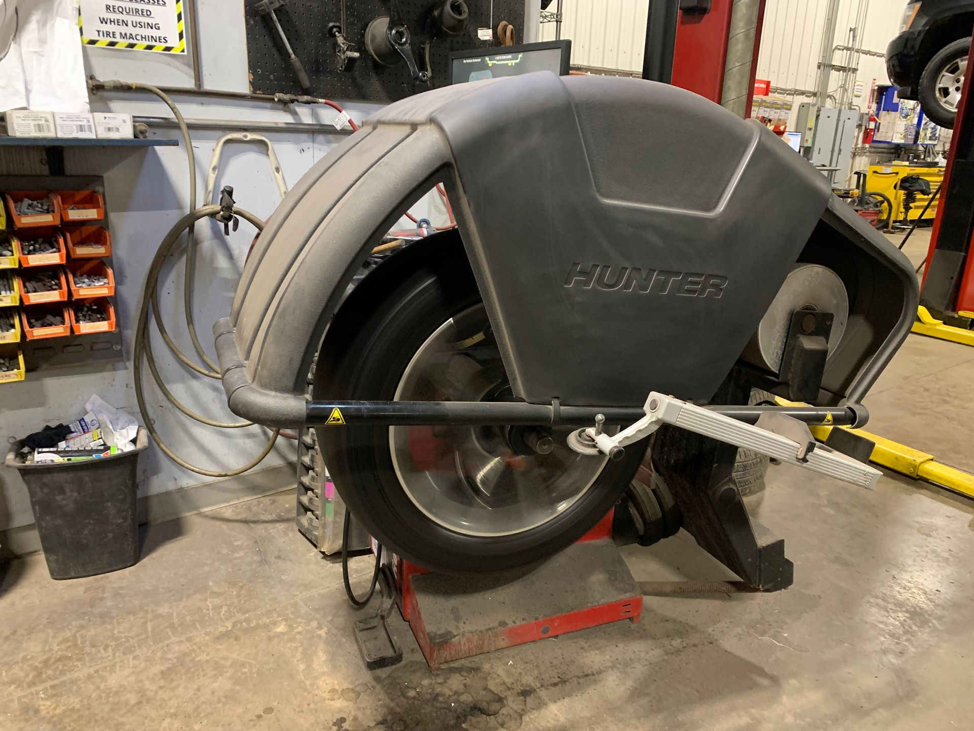 A tire is being balanced on a machine in a garage. | Lou's Car Care