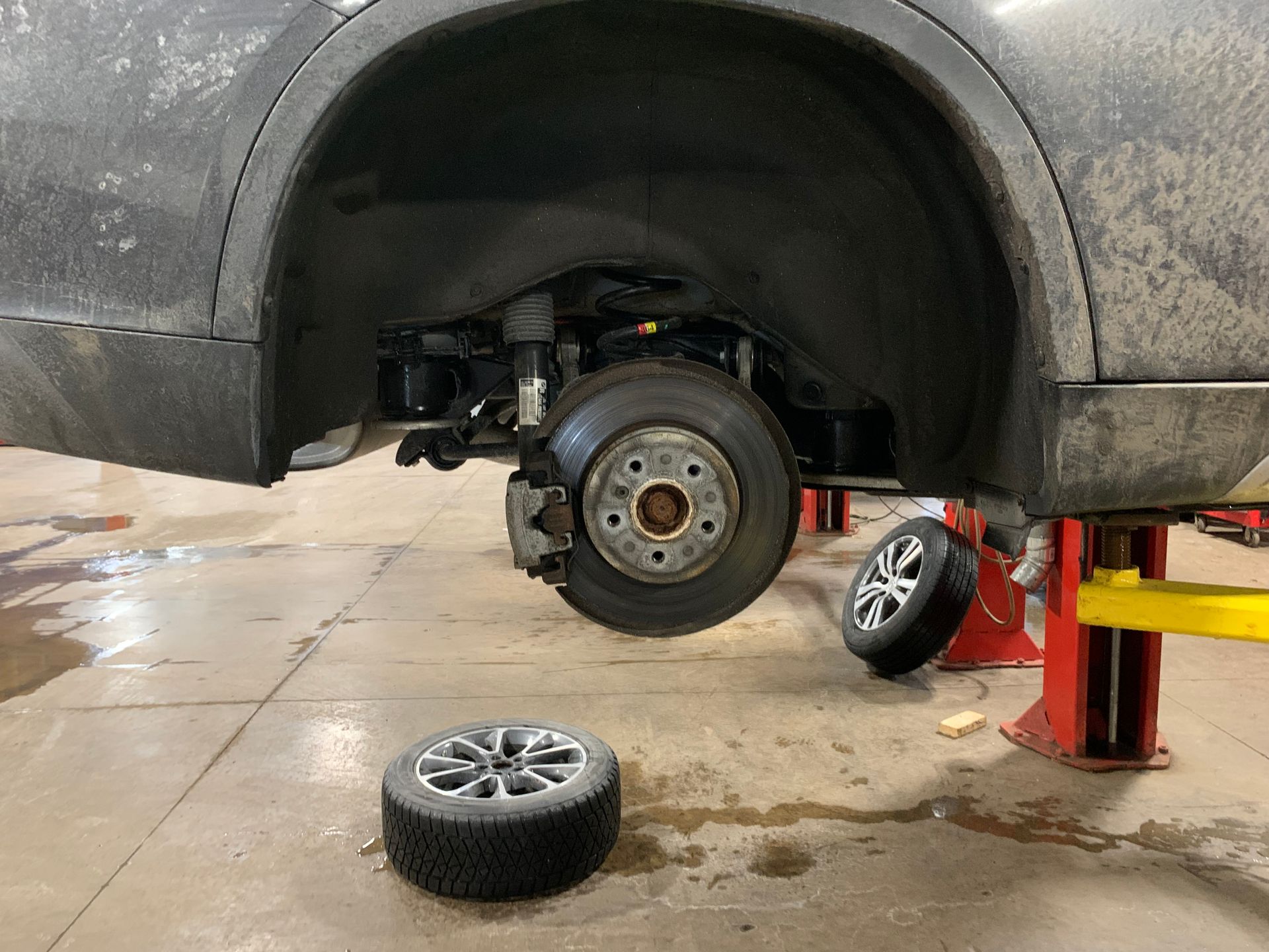 A car is sitting on a lift with a tire on the ground. | Lou's Car Care