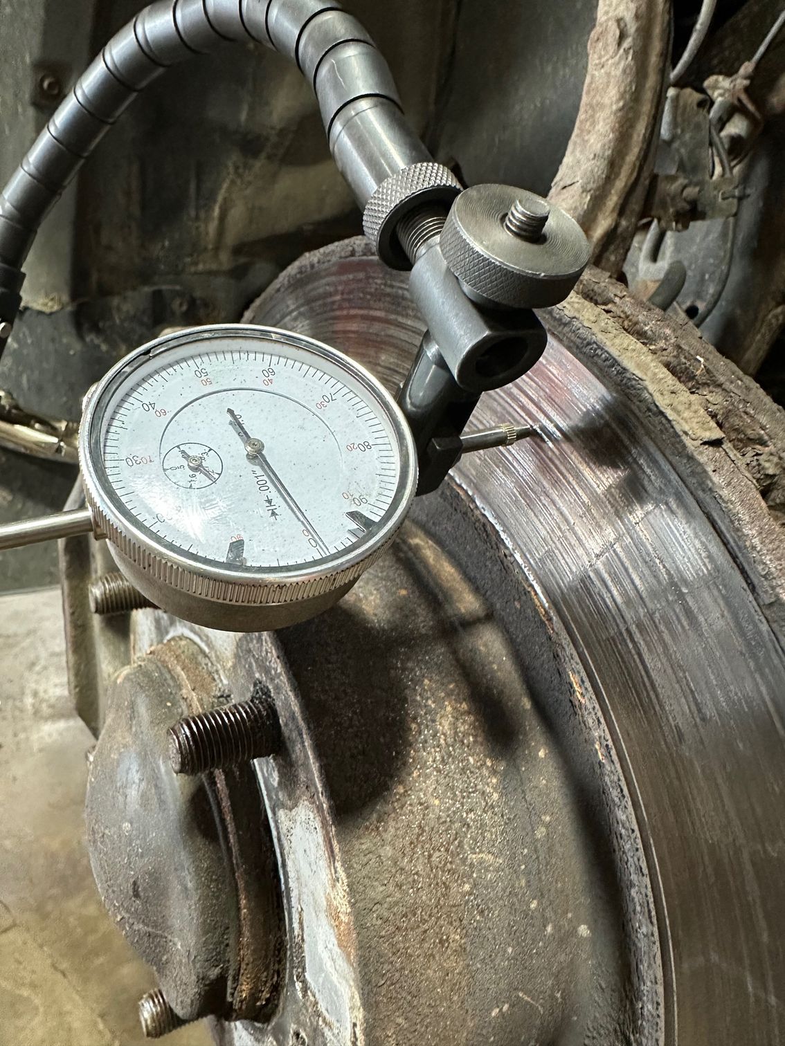 Mechanic measuring brake rotor runout with dial indicator tool.